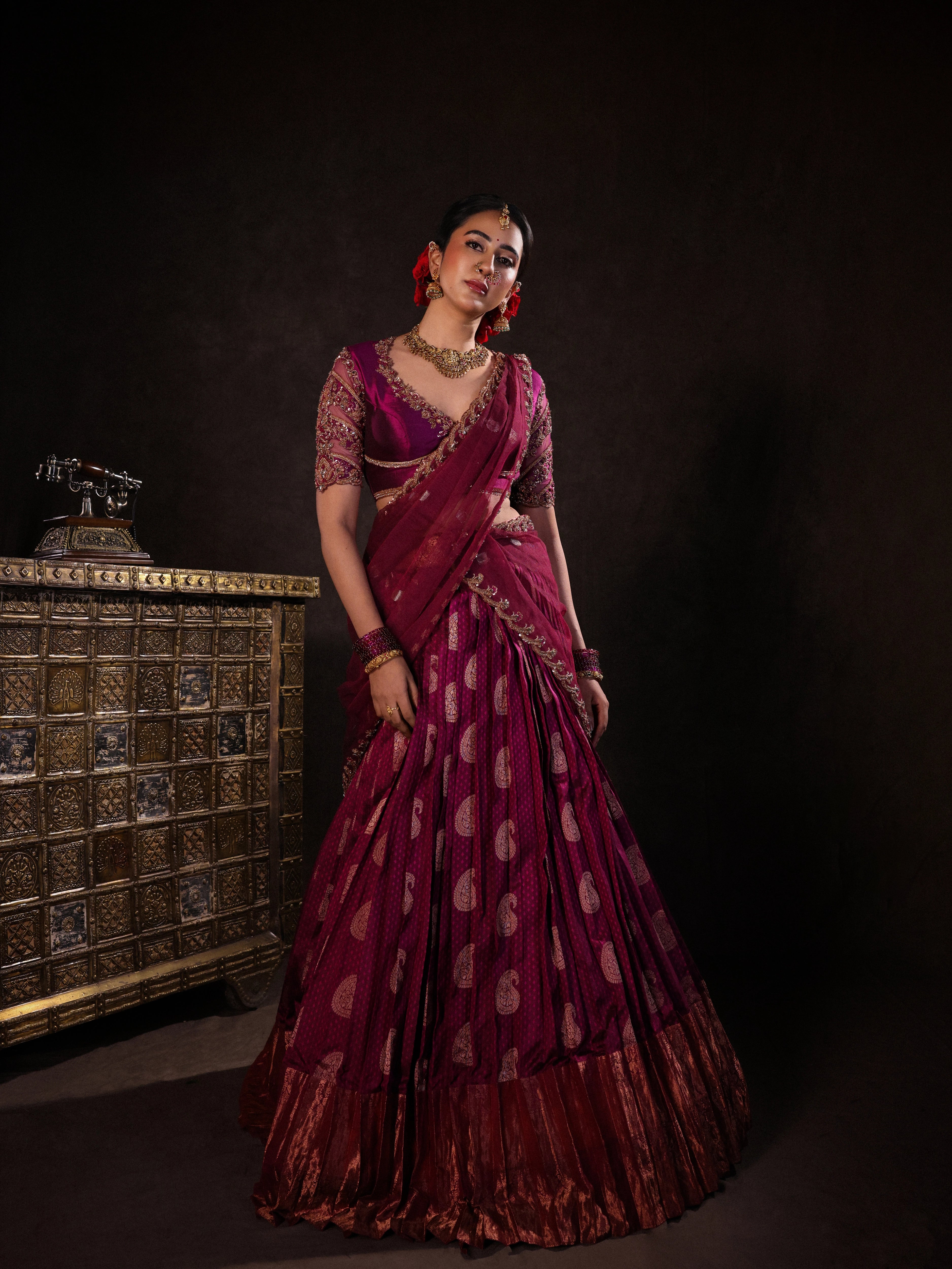 Actress Akshaya Hariharan in a dark magenta silk half saree set handcrafted with zardozi, resham, cutdana, sequins & rhinestones. Team Archana Karthick completed the style with dark magenta glass bangles, a ring, jhumkas, nose ring and a maang tikka.