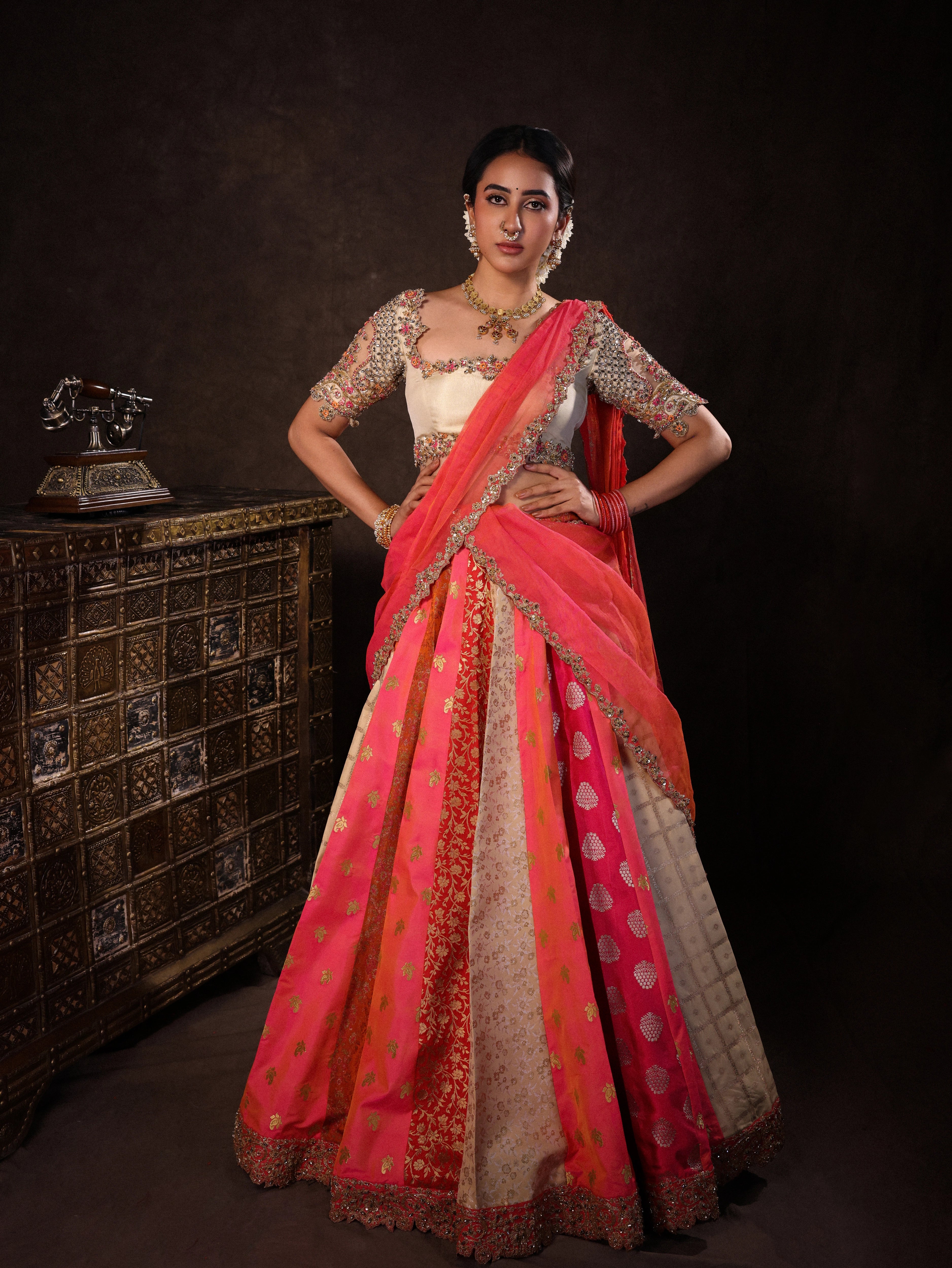 Actress Akshaya Hariharan in an ivory & pink brocade half saree set with tulle sleeves & dupatta. Team Archana Karthick completed the style with purple glass bangles, a ring, jhumkas, nose ring and a maang tikka.