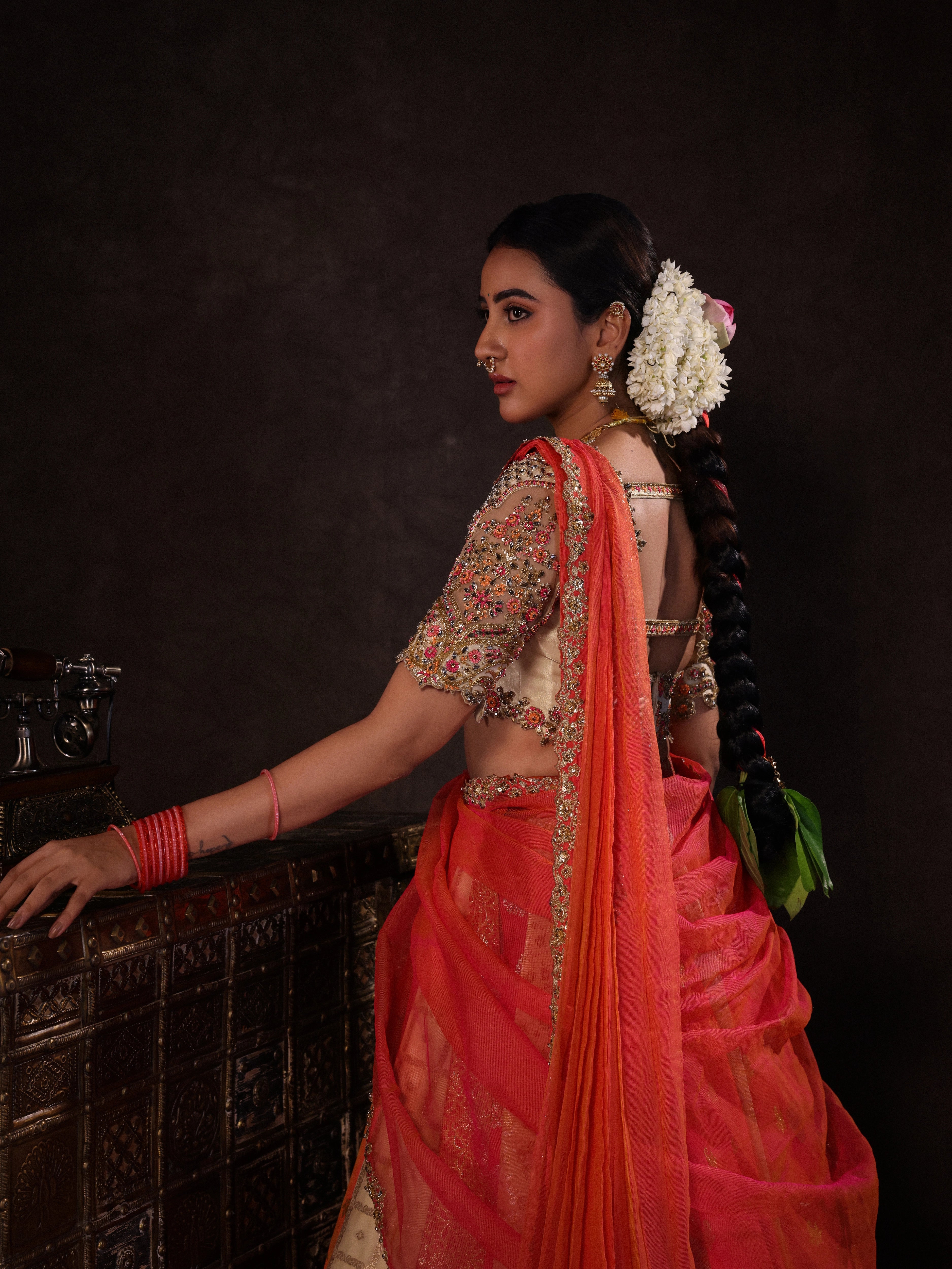 Actress Akshaya Hariharan posing for sleeve & dupatta detailing in an ivory & pink brocade half saree set with tulle sleeves & dupatta. Team Archana Karthick completed the style with purple glass bangles, a ring, jhumkas, nose ring and a maang tikka.
