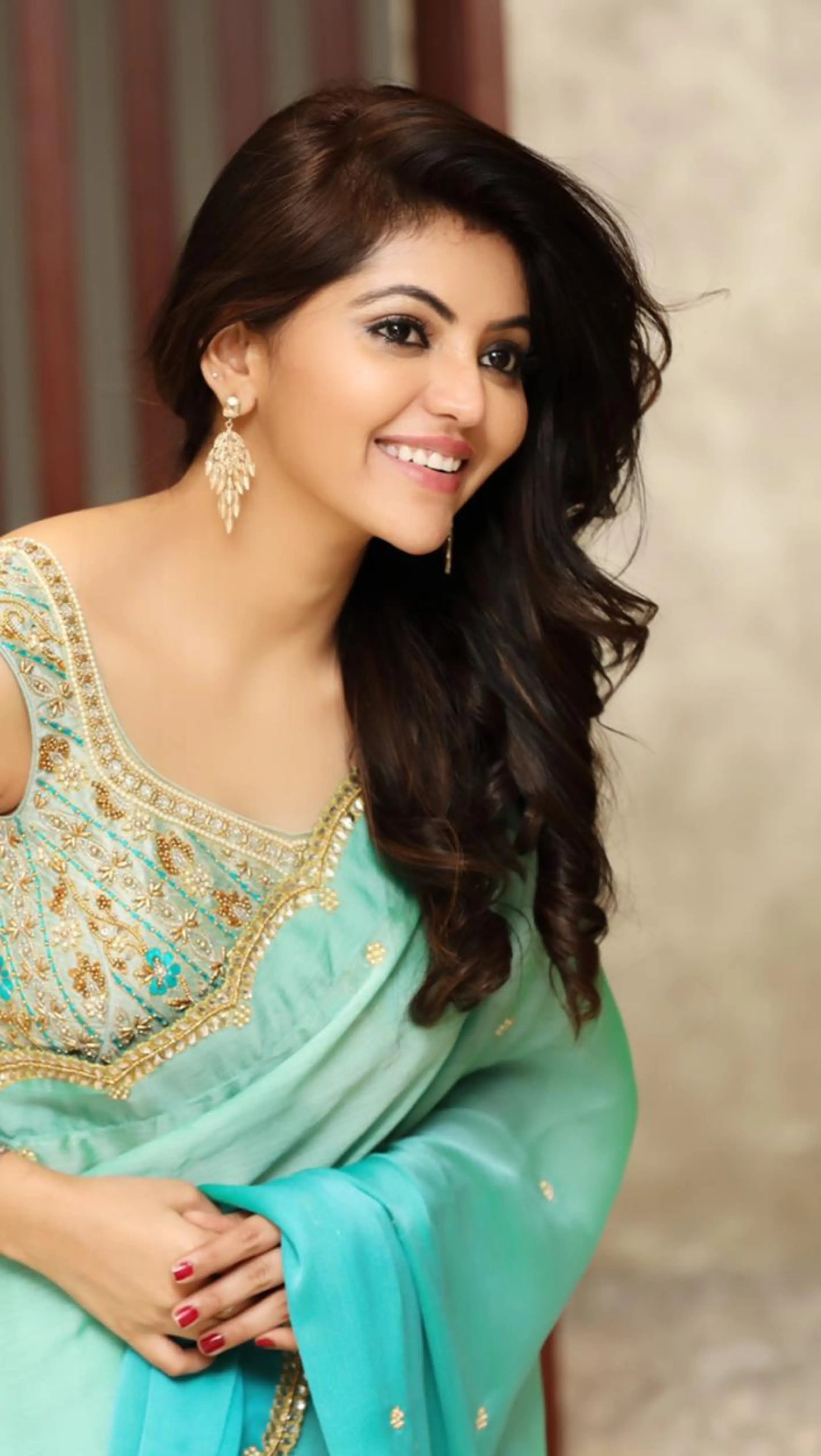 Actress Athulya Ravi smiling in a green georgette saree and raw silk sleeveless blouse, handcrafted with beads, stones, cutdana and resham by team Archana Karthick.