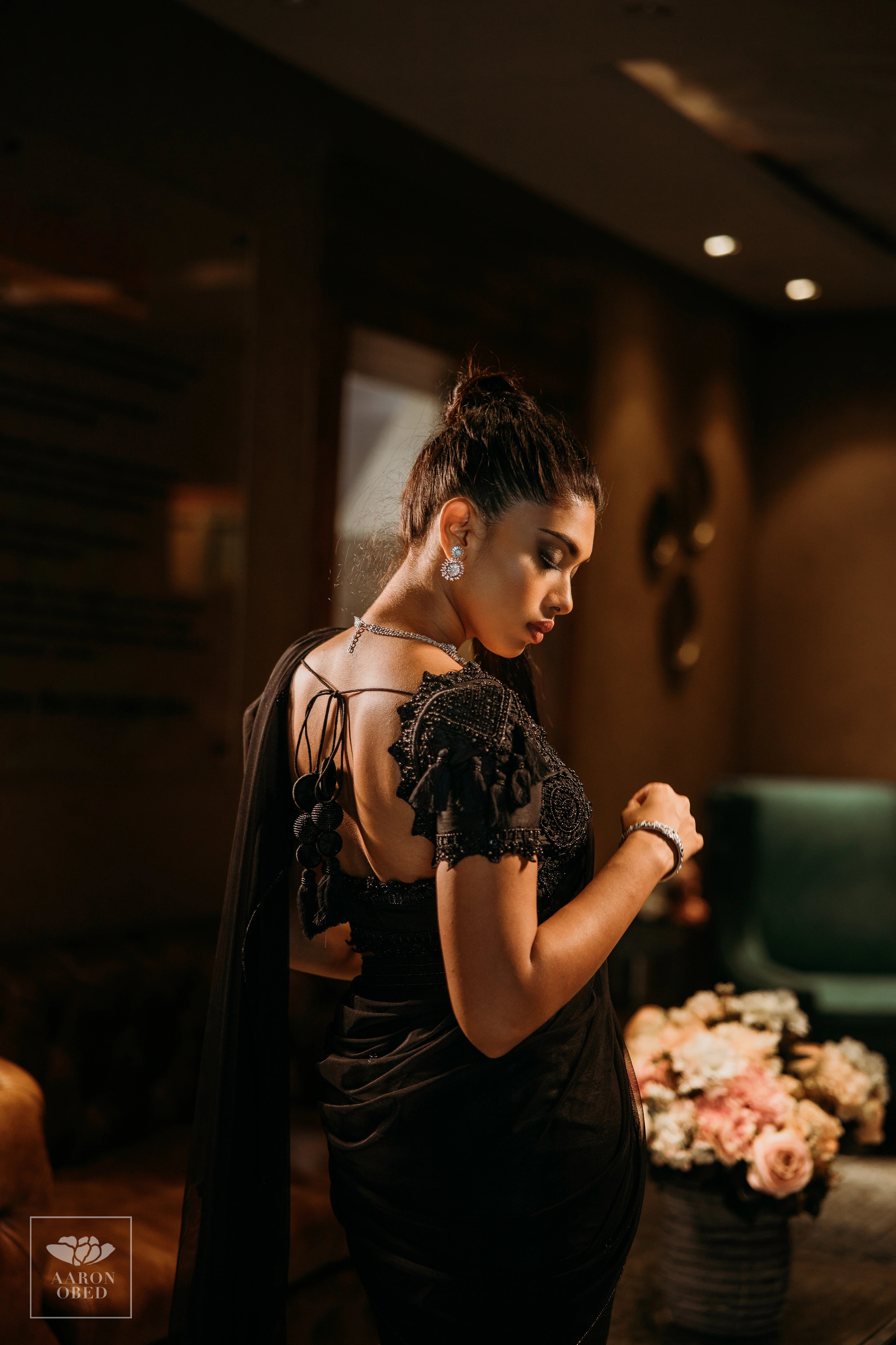 Actress Dushara Vijayan showcasing back blouse design in a black tulle and raw silk draped mermaid lehenga, intricately handcrafted with beads, sequins and resham by team Archana Karthick.
