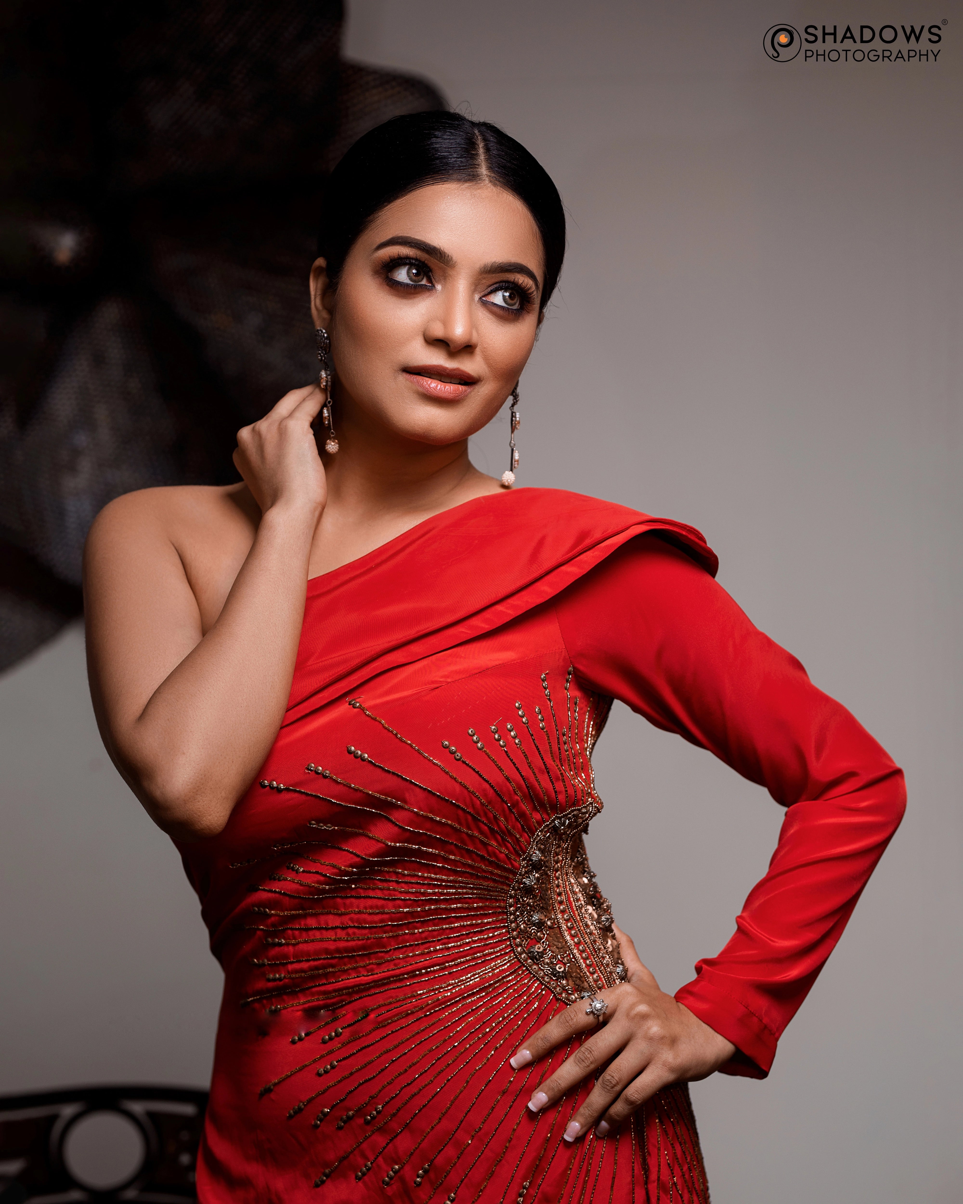 Actress Janai Iyer looking away in a red crepe silk one-shoulder asymmetric gown, intricately handcrafted with sequins, zardozi, cutdana and beads by team Archana Karthick.