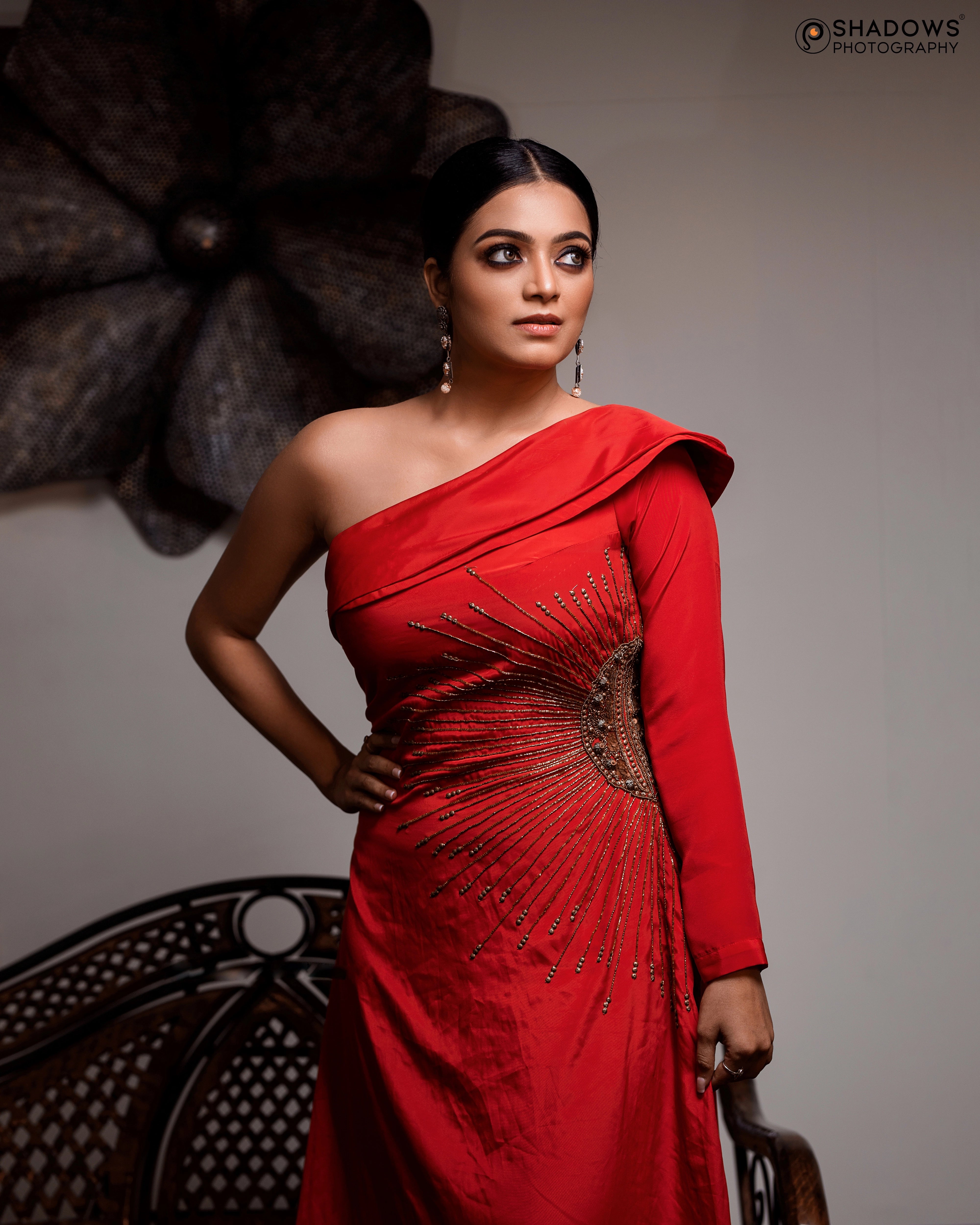 Actress Janai Iyer posing in a red crepe silk one-shoulder asymmetric gown, intricately handcrafted with sequins, zardozi, cutdana and beads by team Archana Karthick.