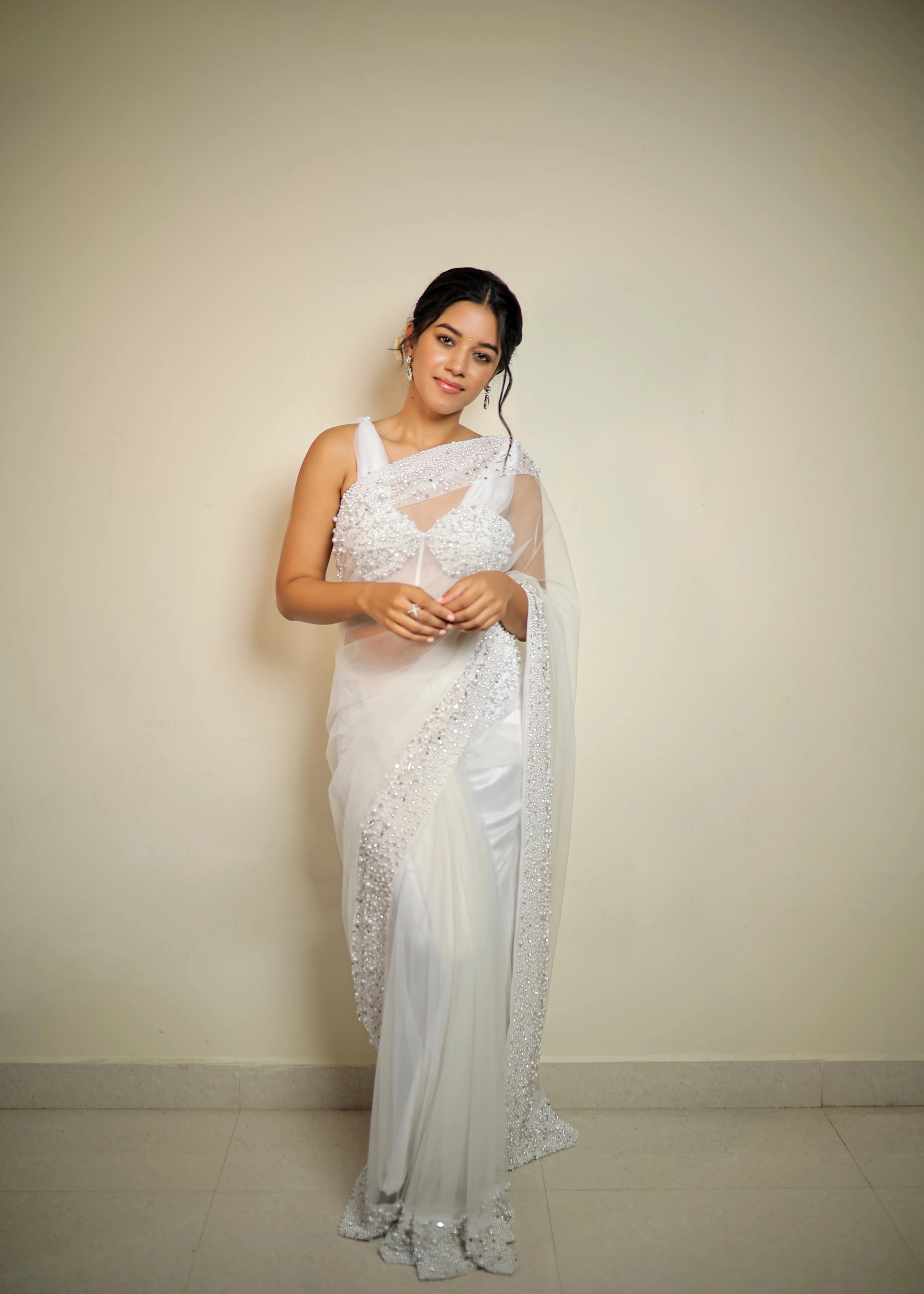 Actress Mirnalini Ravi in a pearl white saree intricately embellished with pearls and cut beads, paired with an off-shoulder corset with cowl sleeves.