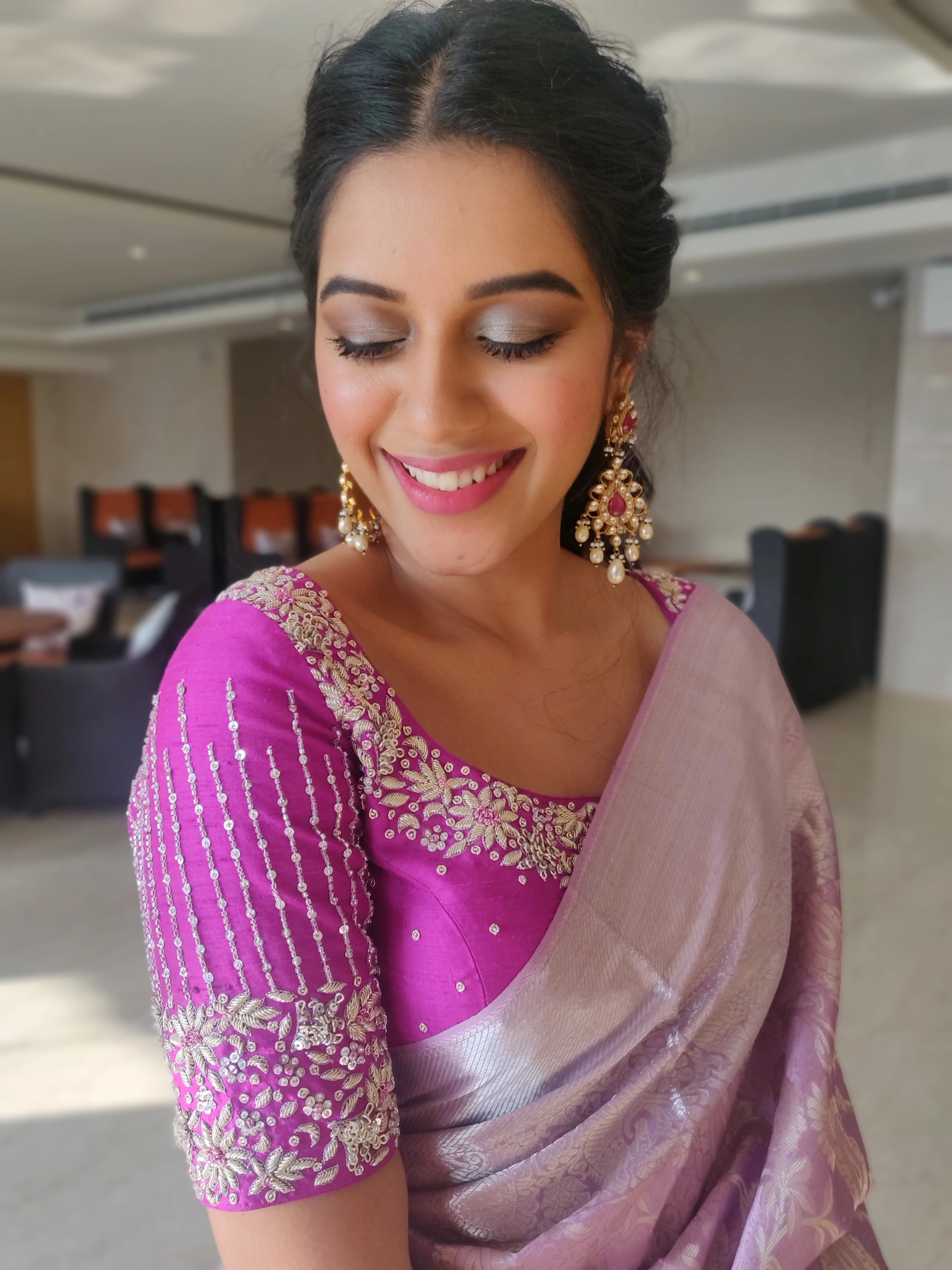 Actress Mirnalini Ravi looking down in a magenta raw silk blouse designed by Archana Karthick handcrafted intricately with zardozi, sequins and stones.
