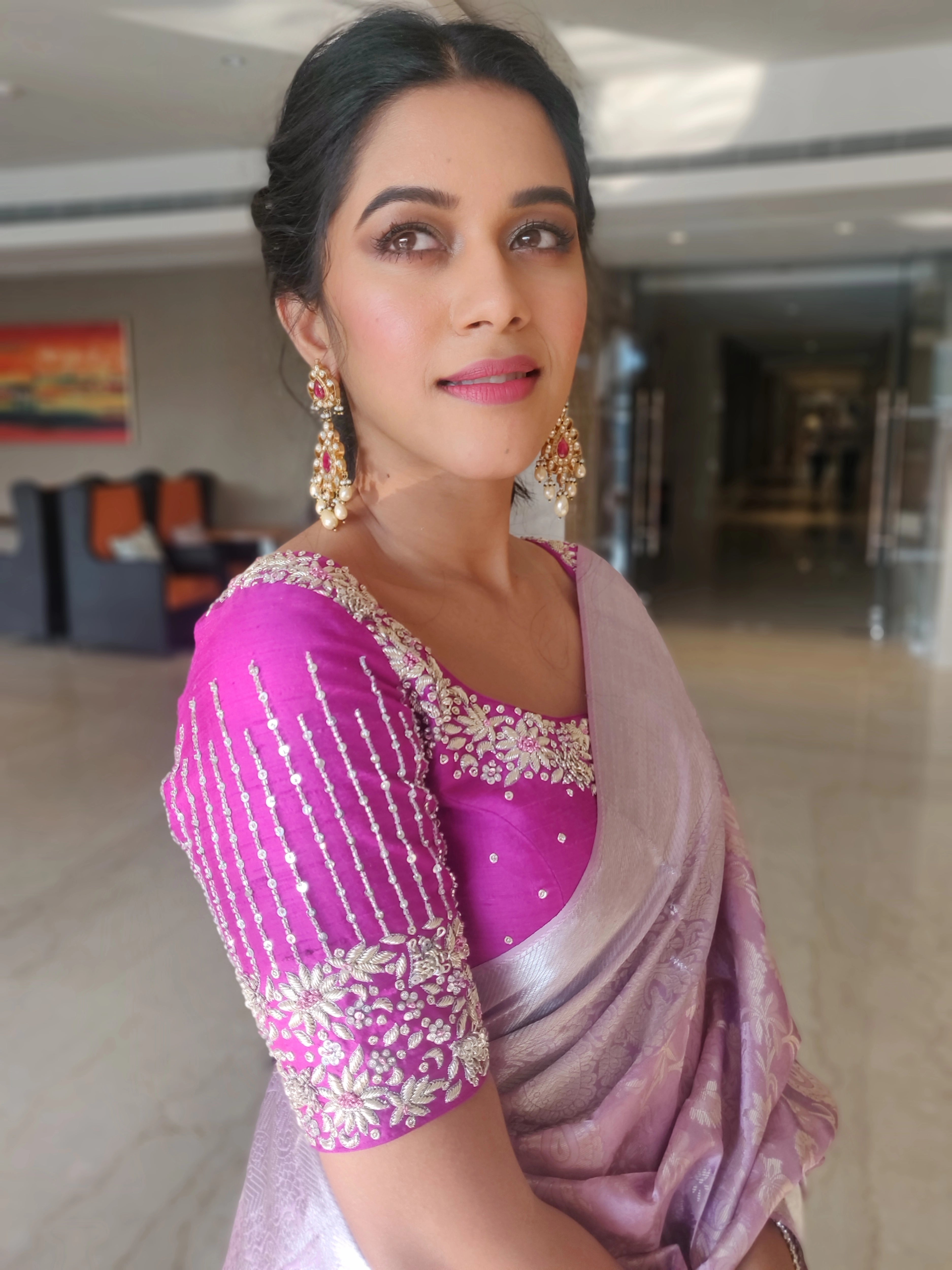 Actress Mirnalini Ravi posing sideways in a magenta raw silk blouse designed by Archana Karthick handcrafted intricately with zardozi, sequins and stones.