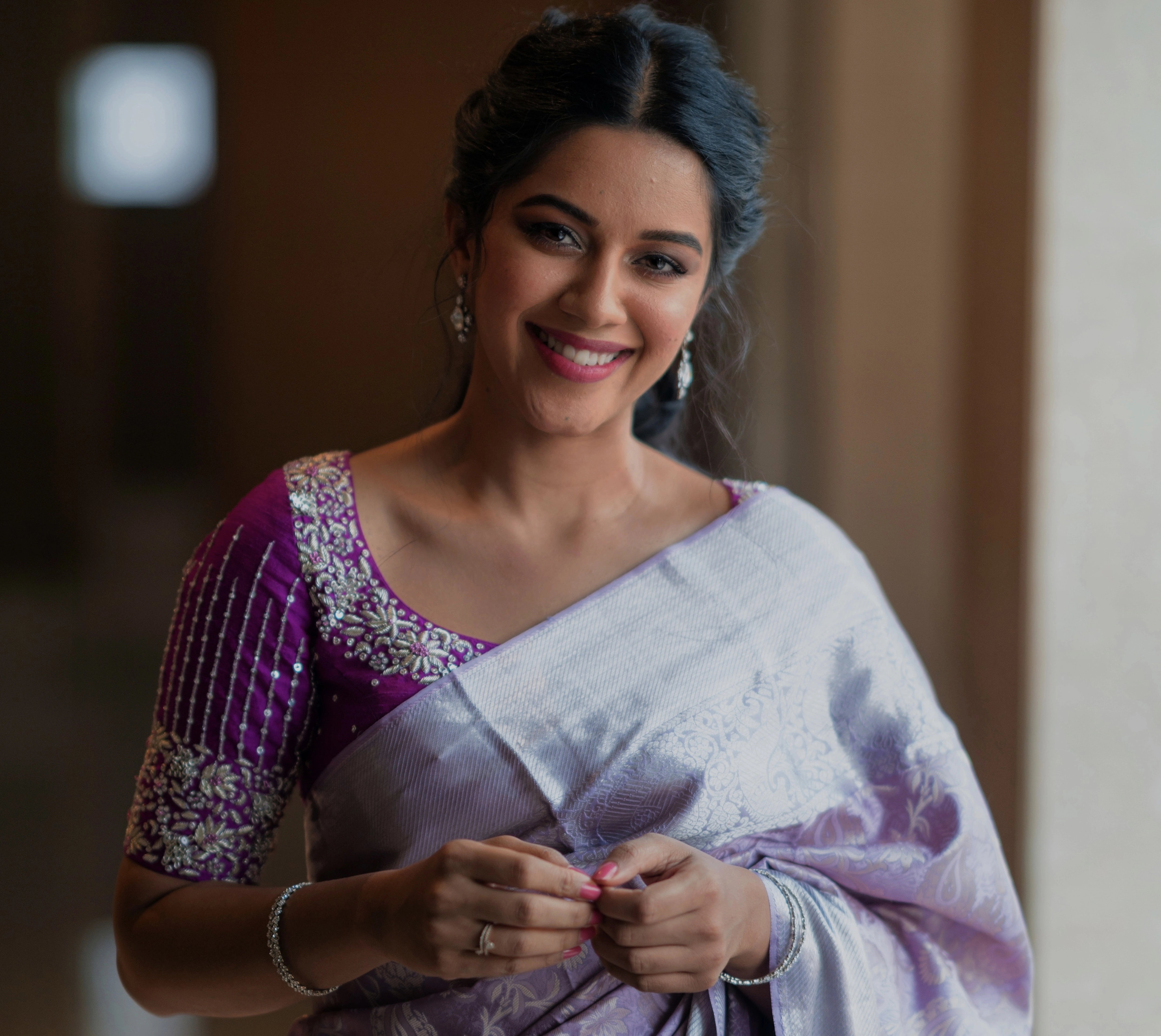 Actress Mirnalini Ravi smiling in a magenta raw silk blouse designed by Archana Karthick handcrafted intricately with zardozi, sequins and stones.