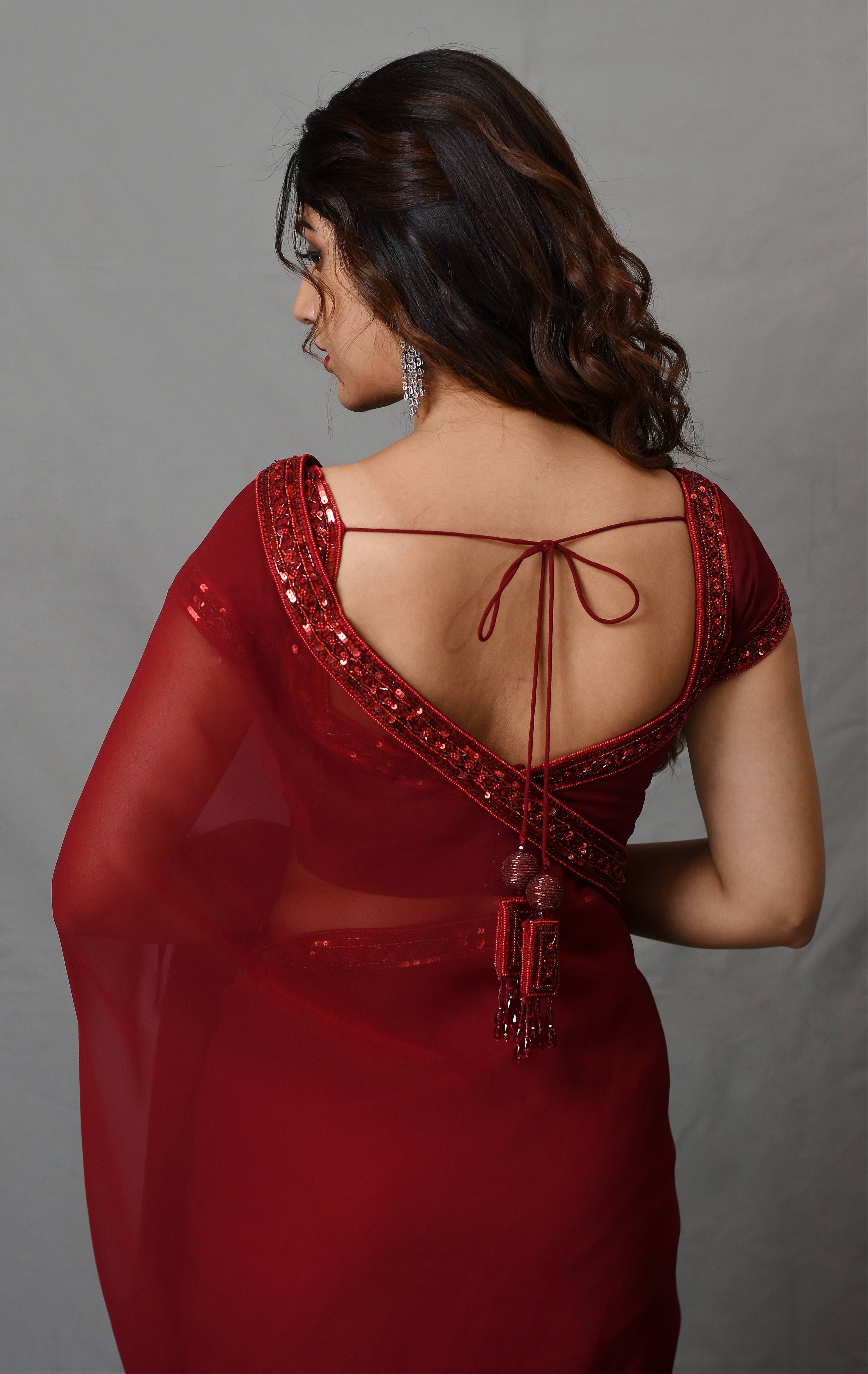 Actress Rabiya Khatoon in a ruby red georgette saree set designed by Archana Karthick. Back blouse design and tassels.