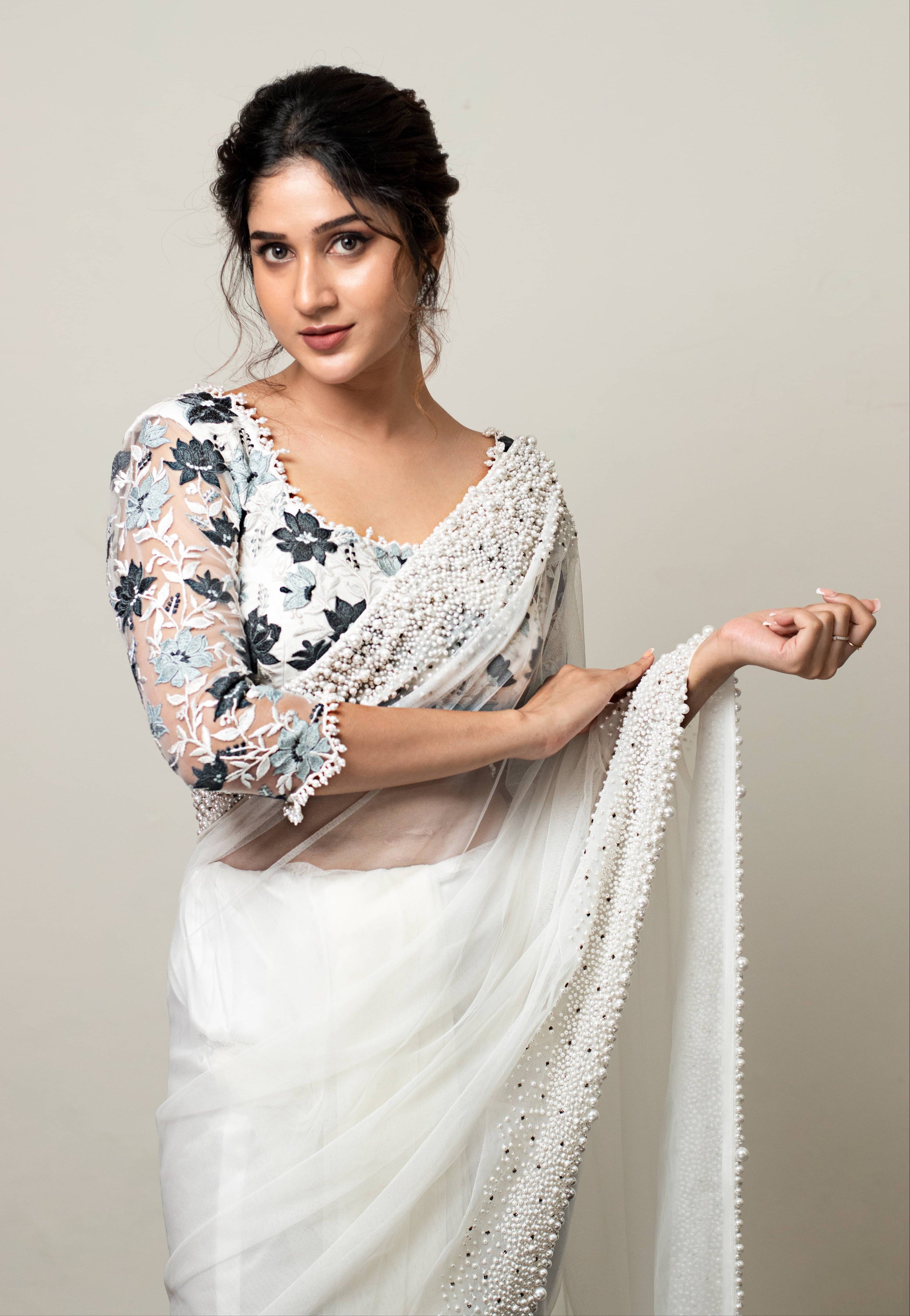 Actress Rabiya Khatoon in white net saree with pearl embellished border and blue florals in resham full sleeved blouse. Half front profile saree and blouse closeup.