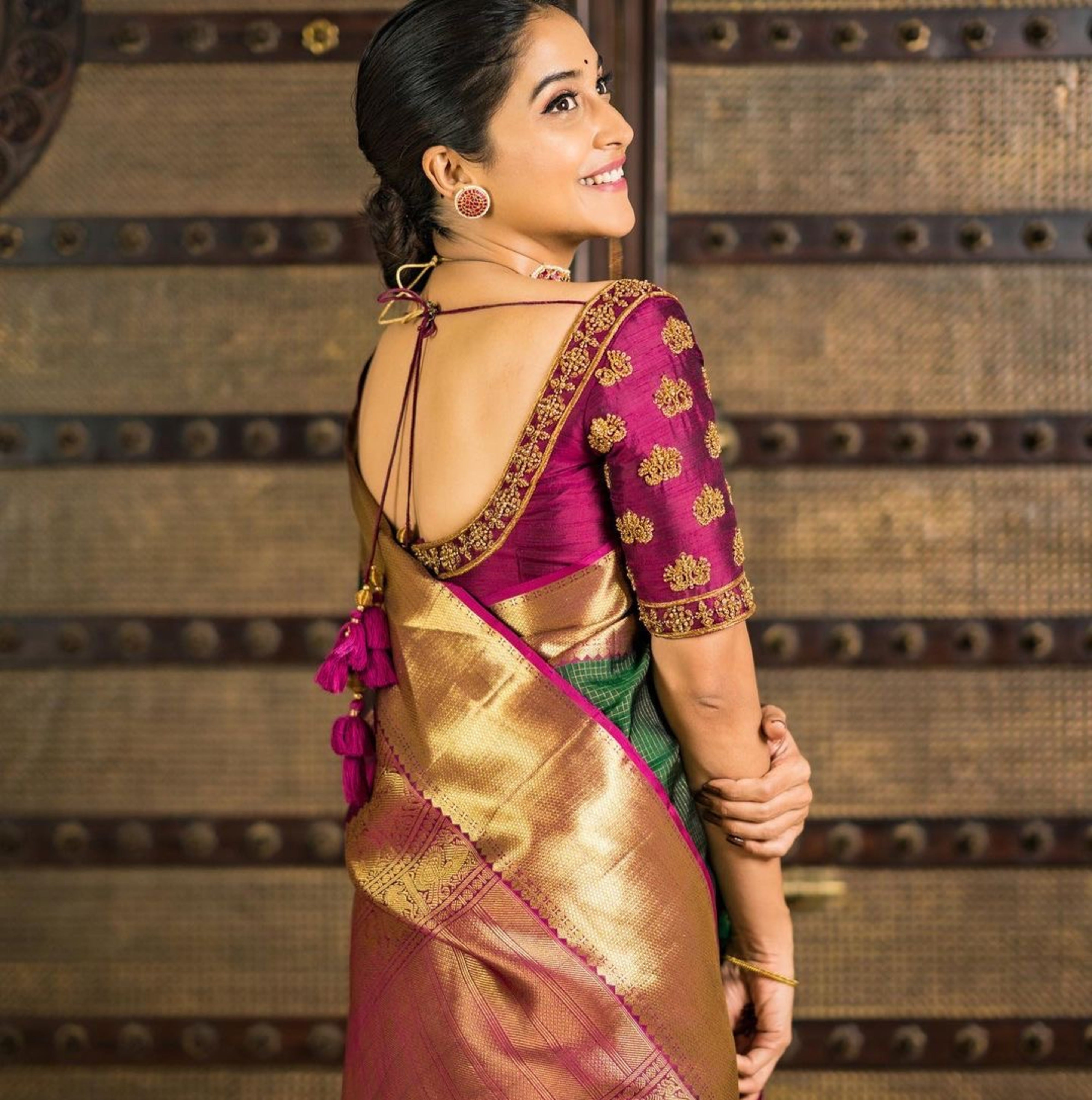 Actress Regina Cassandra in a wine red raw silk blouse designed by Archana Karthick. The blouse is handcrafted with zardozi work. Back blouse design and neckline is seen.