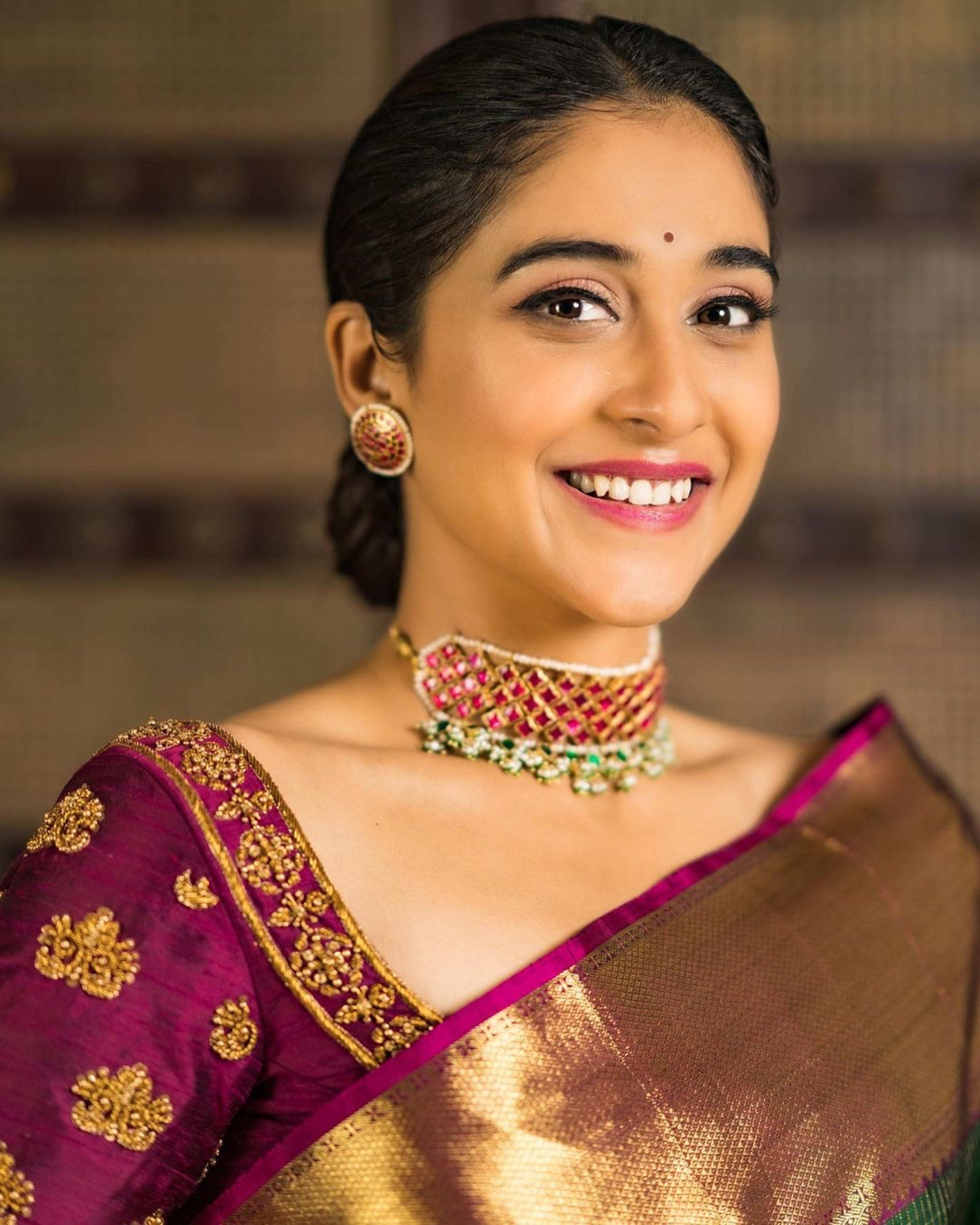 Actress Regina Cassandra in a wine red raw silk blouse designed by Archana Karthick. The blouse is handcrafted with zardozi work. Neckline and upper sleeve is seen.