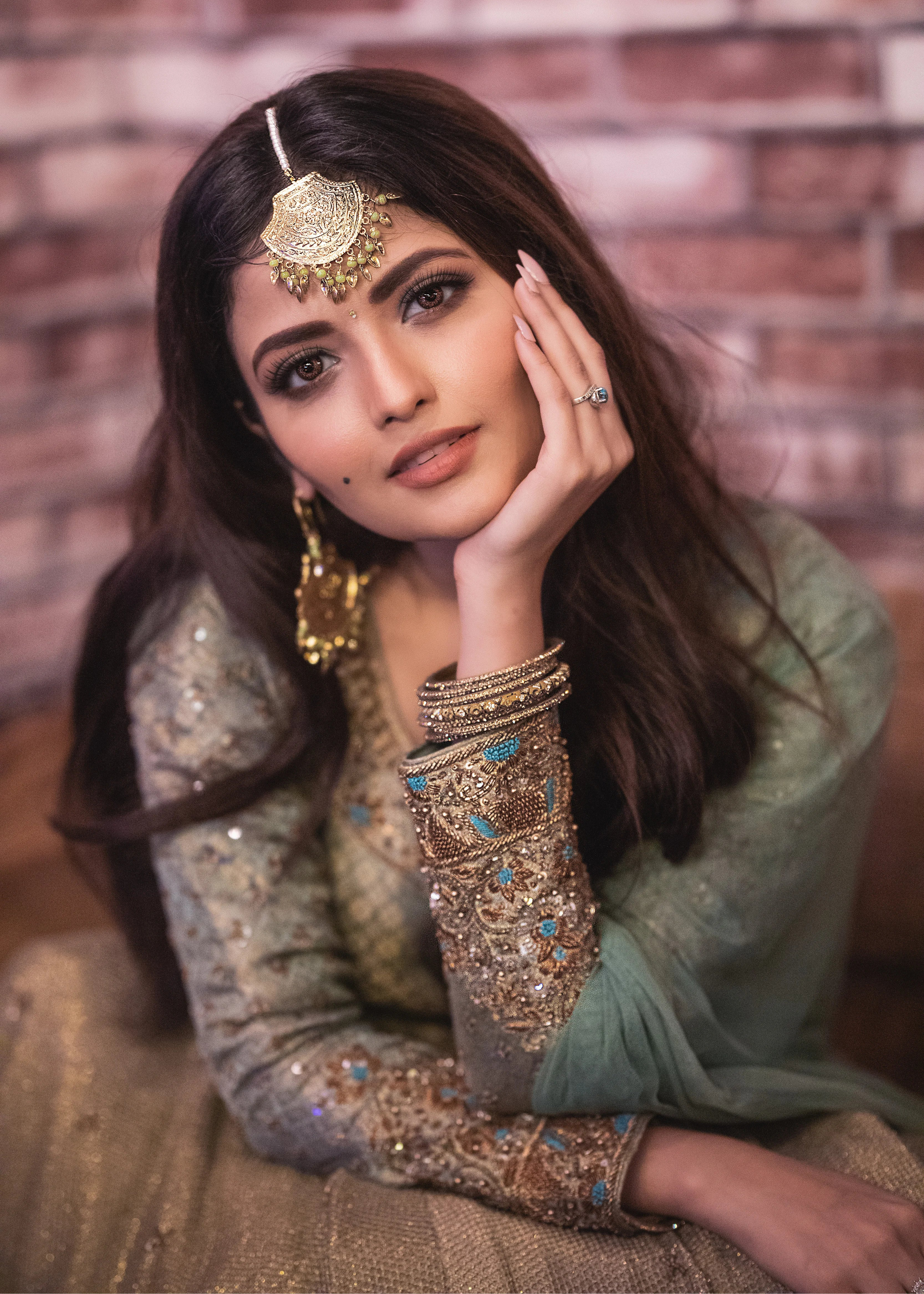 Actress Shirin Kanchwala in a handcrafted banaras (brocade) lehenga in shades of light sea green / pista blue / cyan designed by Archana Karthick looking at camera with hand on face