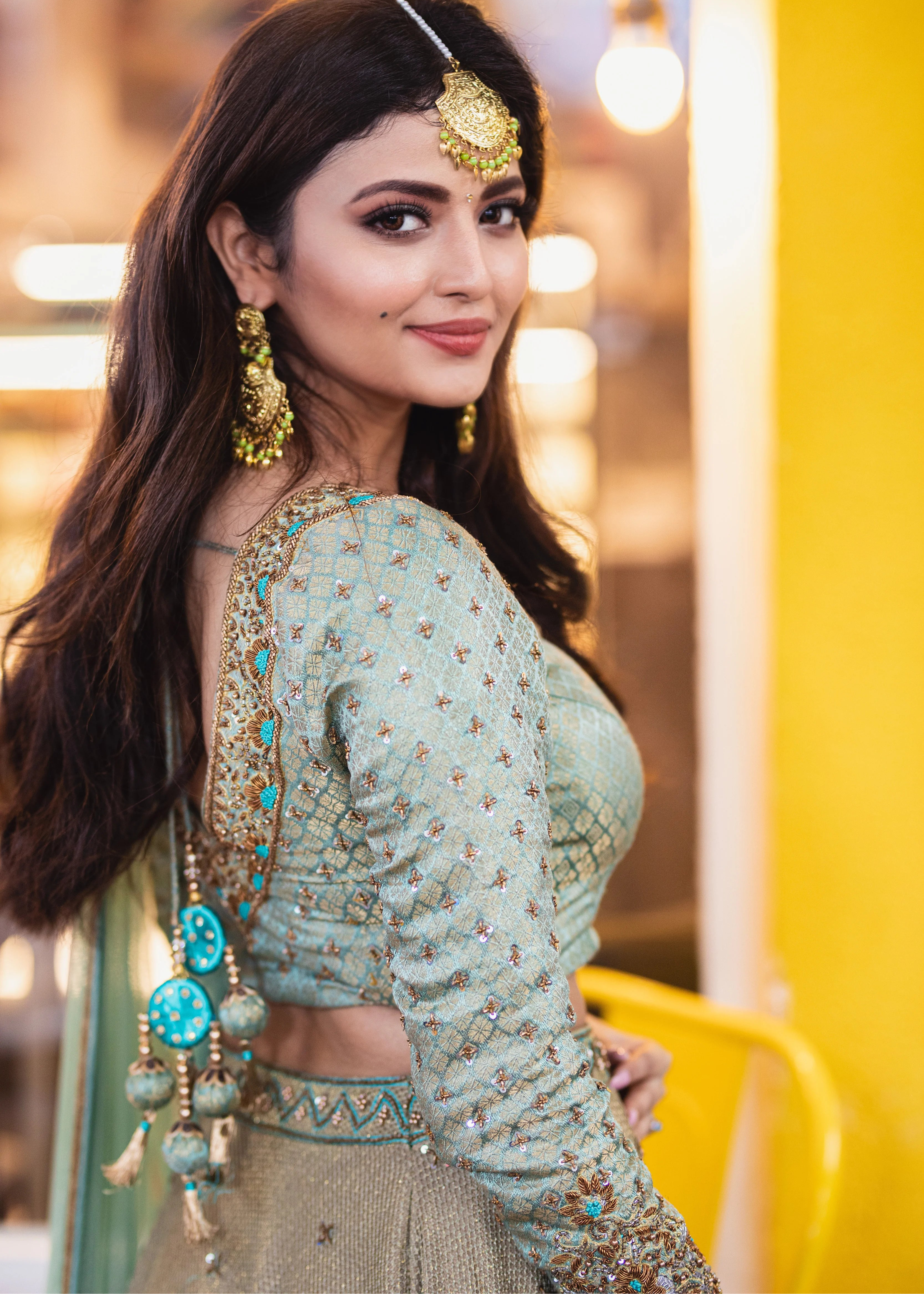 Actress Shirin Kanchwala in a handcrafted banaras (brocade) lehenga in shades of light sea green / pista blue / cyan designed by Archana Karthick posing for blouse back and tassel design