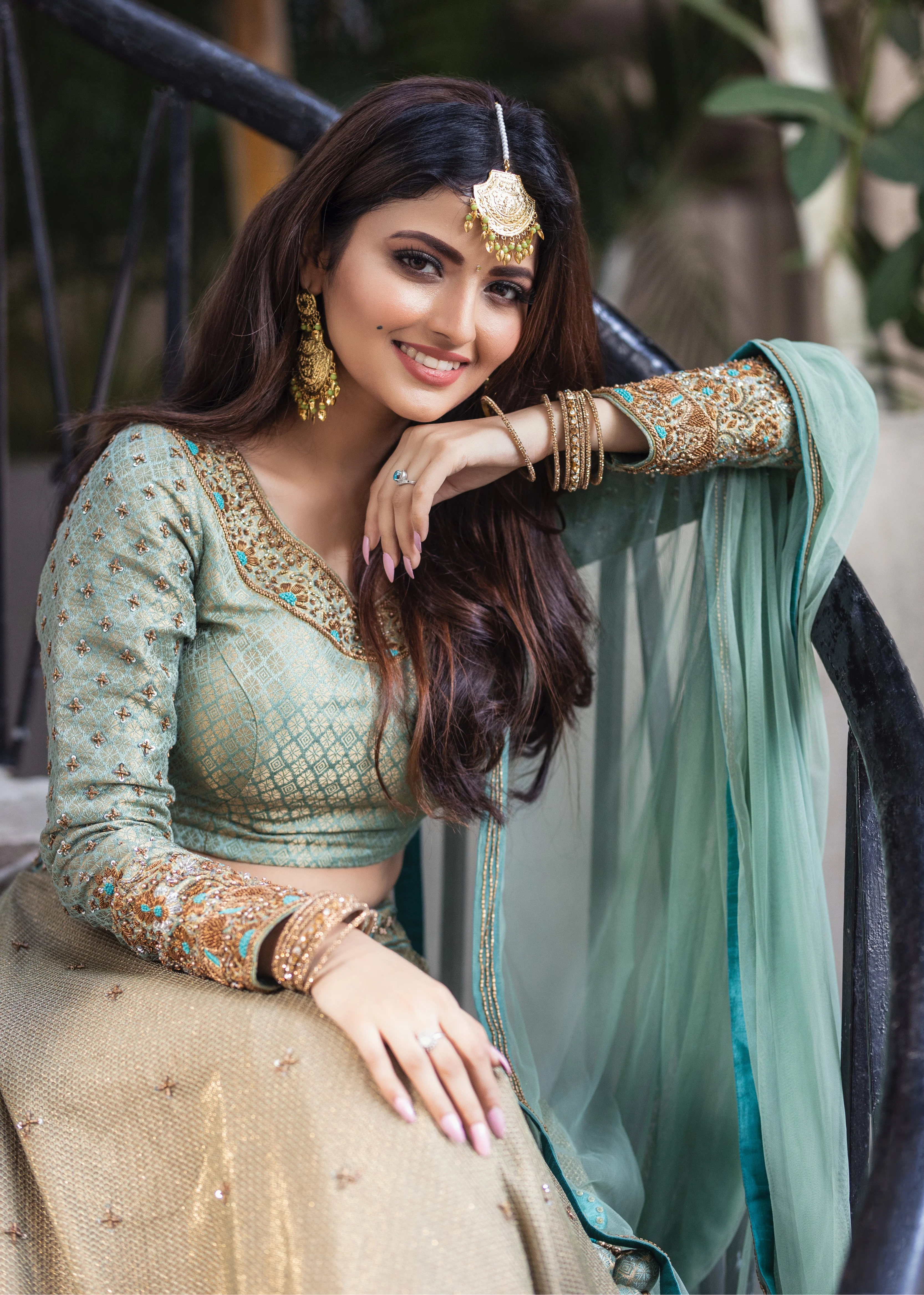 Actress Shirin Kanchwala in a handcrafted banaras (brocade) lehenga in shades of light sea green / pista blue / cyan designed by Archana Karthick smiling at the camera with hand on her chin