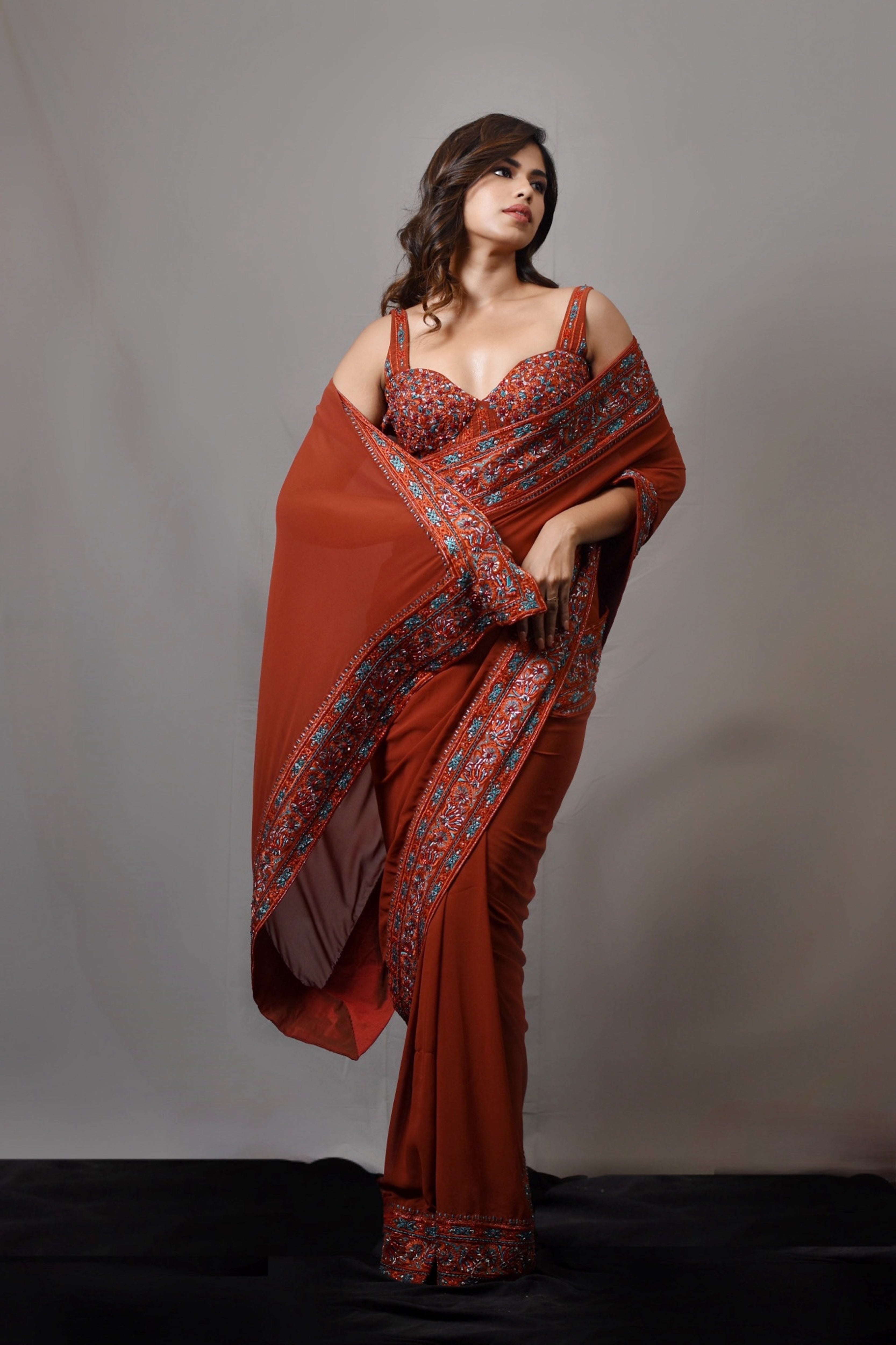 Actress Shrisha in a burnt orange crepe silk saree with an intricately handcrafted border and corset blouse from the Lo-Mance collection by Archana Karthick.
