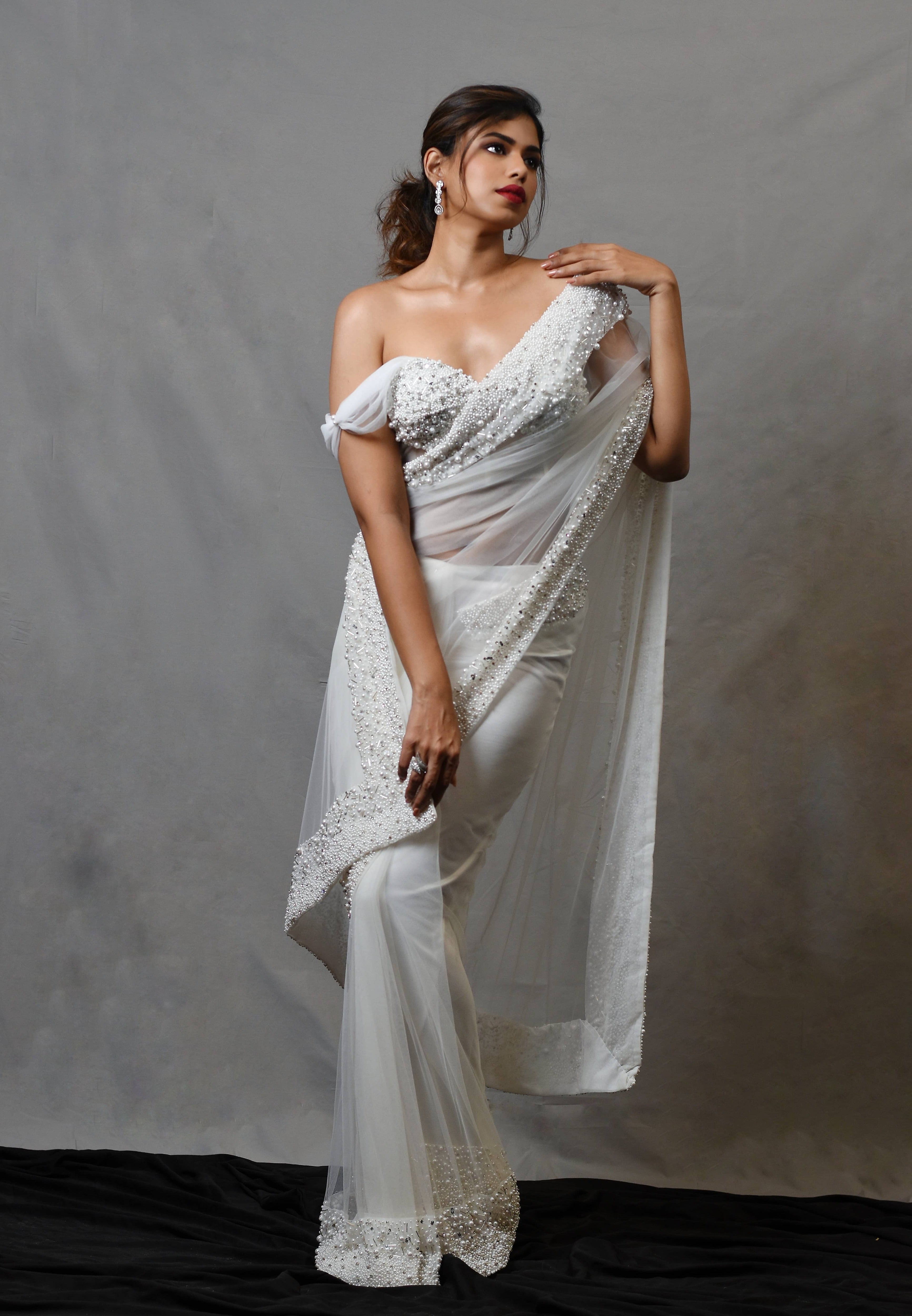 Actress Shrisha the niece of superstar actress Sridevi in a white net saree with embellished border and corset blouse with cowl sleeves.