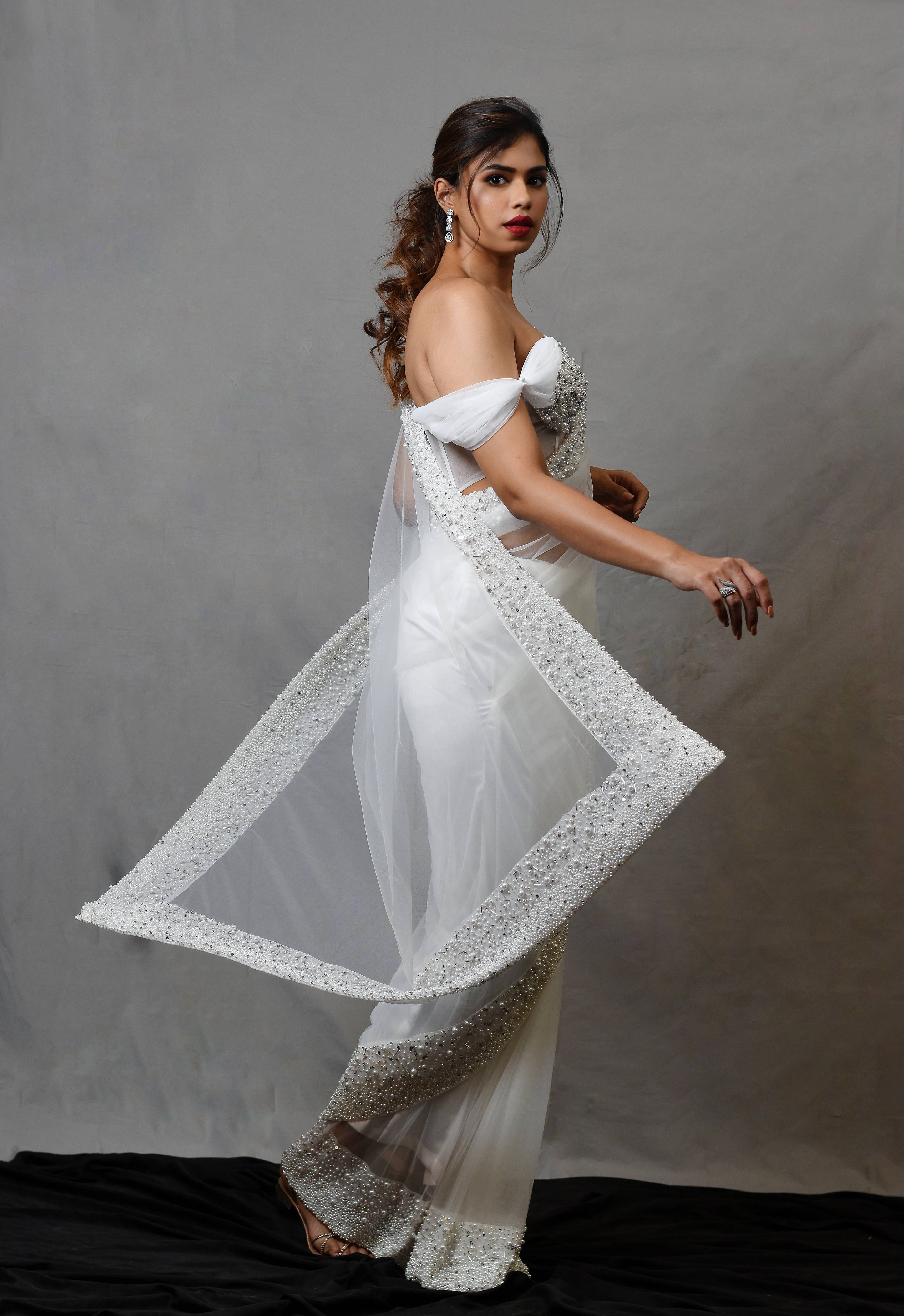 Actress Shrisha the niece of superstar actress Sridevi in a white net saree with embellished border and corset blouse with cowl sleeves. Side profile.