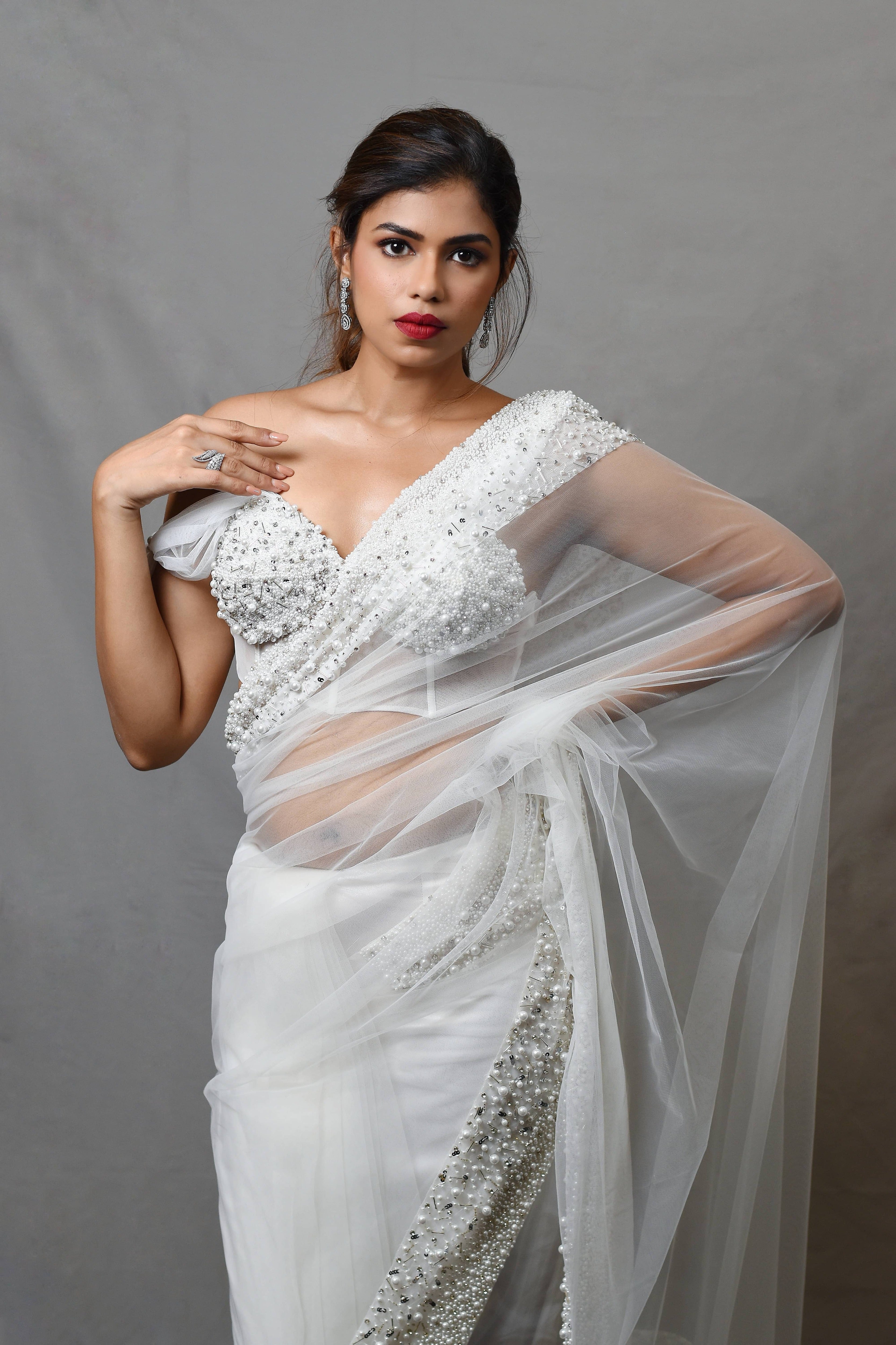 Actress Shrisha the niece of superstar actress Sridevi in a white net saree with embellished border and corset blouse with cowl sleeves. front profile.