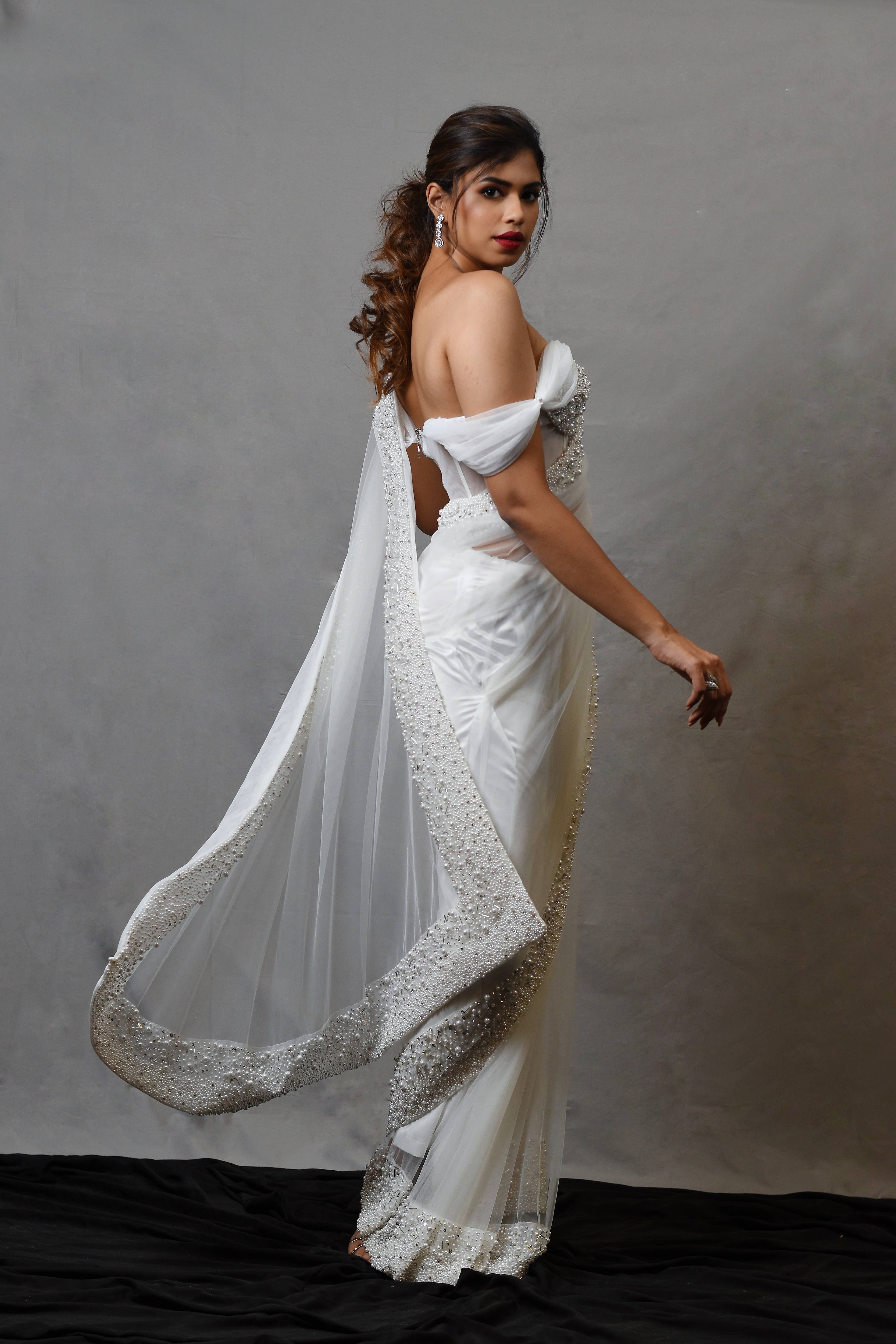 Actress Shrisha the niece of superstar actress Sridevi in a white net saree with embellished border and corset blouse with cowl sleeves. side profile pallu.