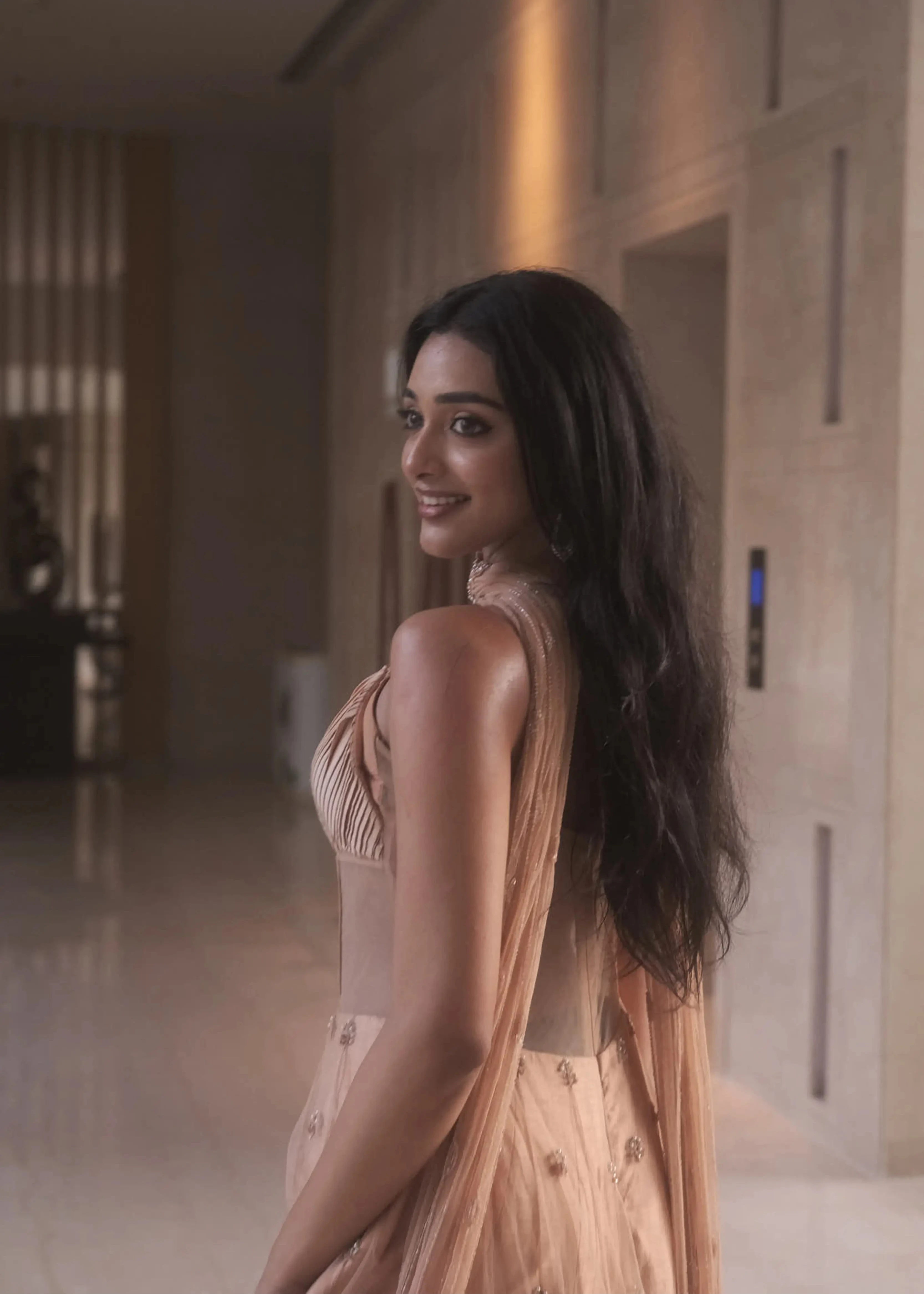 Actress & dancer Preity Mukhundhan posing for back design in a peach corset gown with draped dupatta attached at the neck, intricately handcrafted by team Archana Karthick.