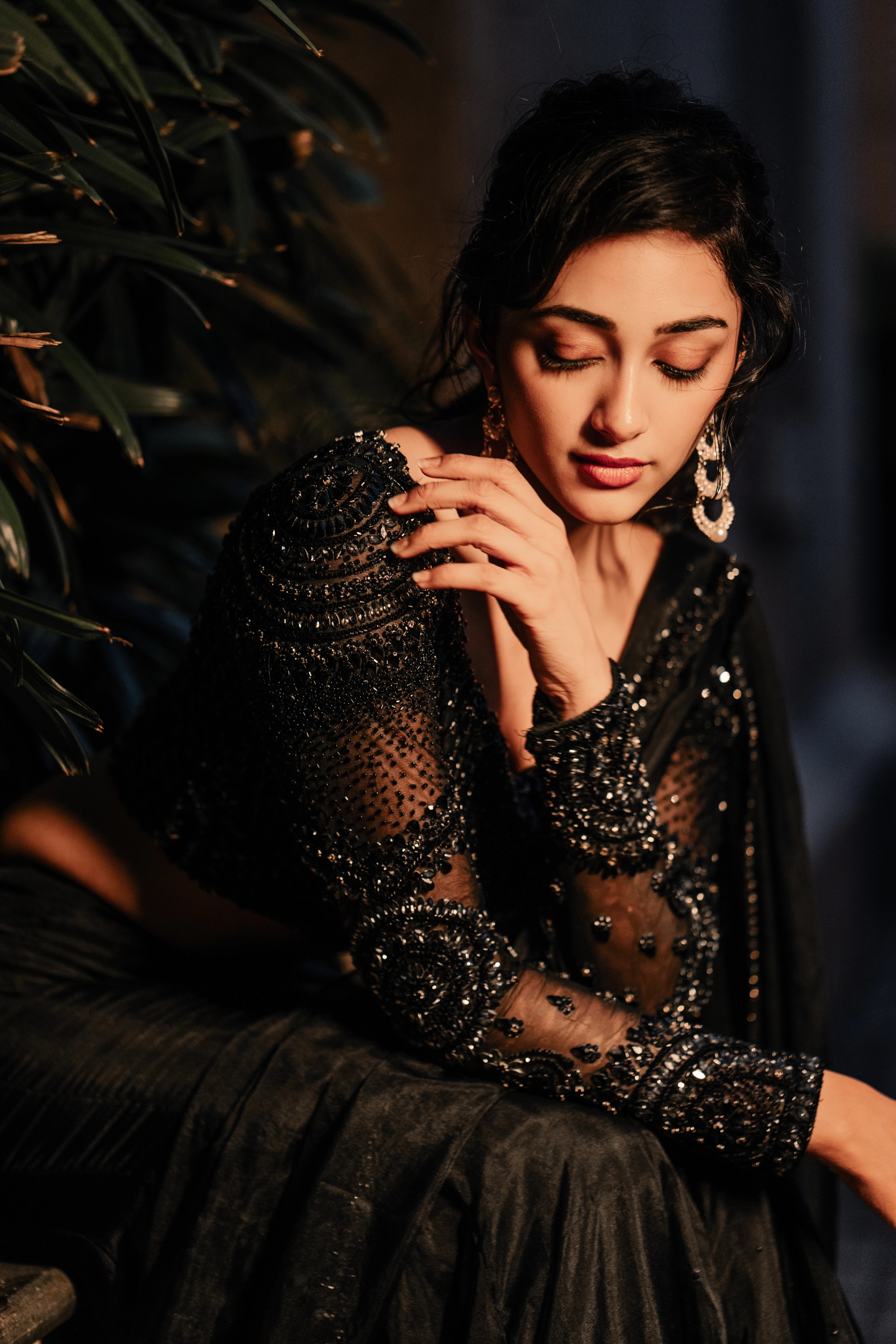 Actress & dancer Preity Mukhundhan posing seated in "The Black Mermaid" black mermaid lehenga saree from Archana Karthick's collection.