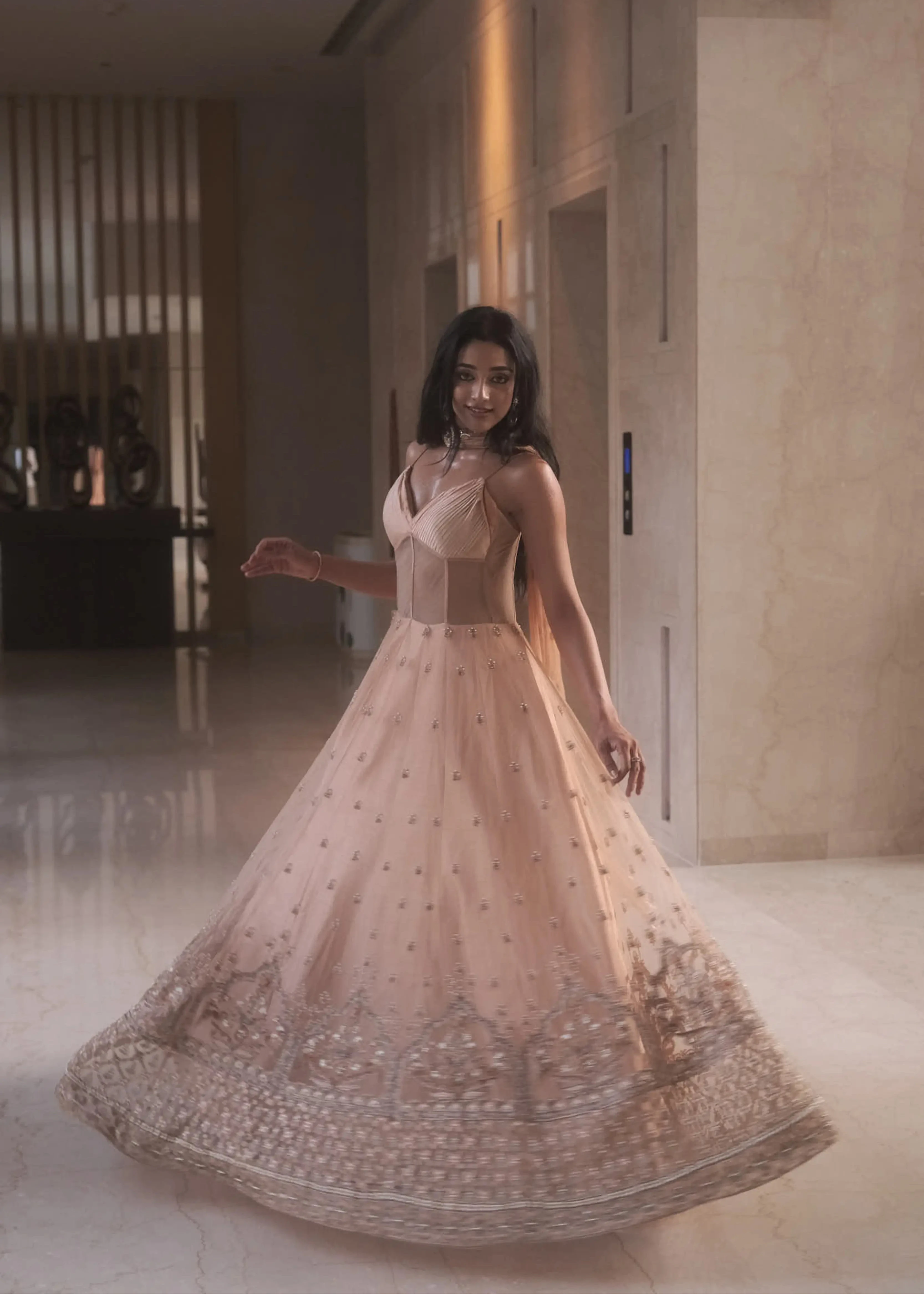 Actress & dancer Preity Mukhundhan twirling in a peach corset gown with draped dupatta attached at the neck, intricately handcrafted by team Archana Karthick.