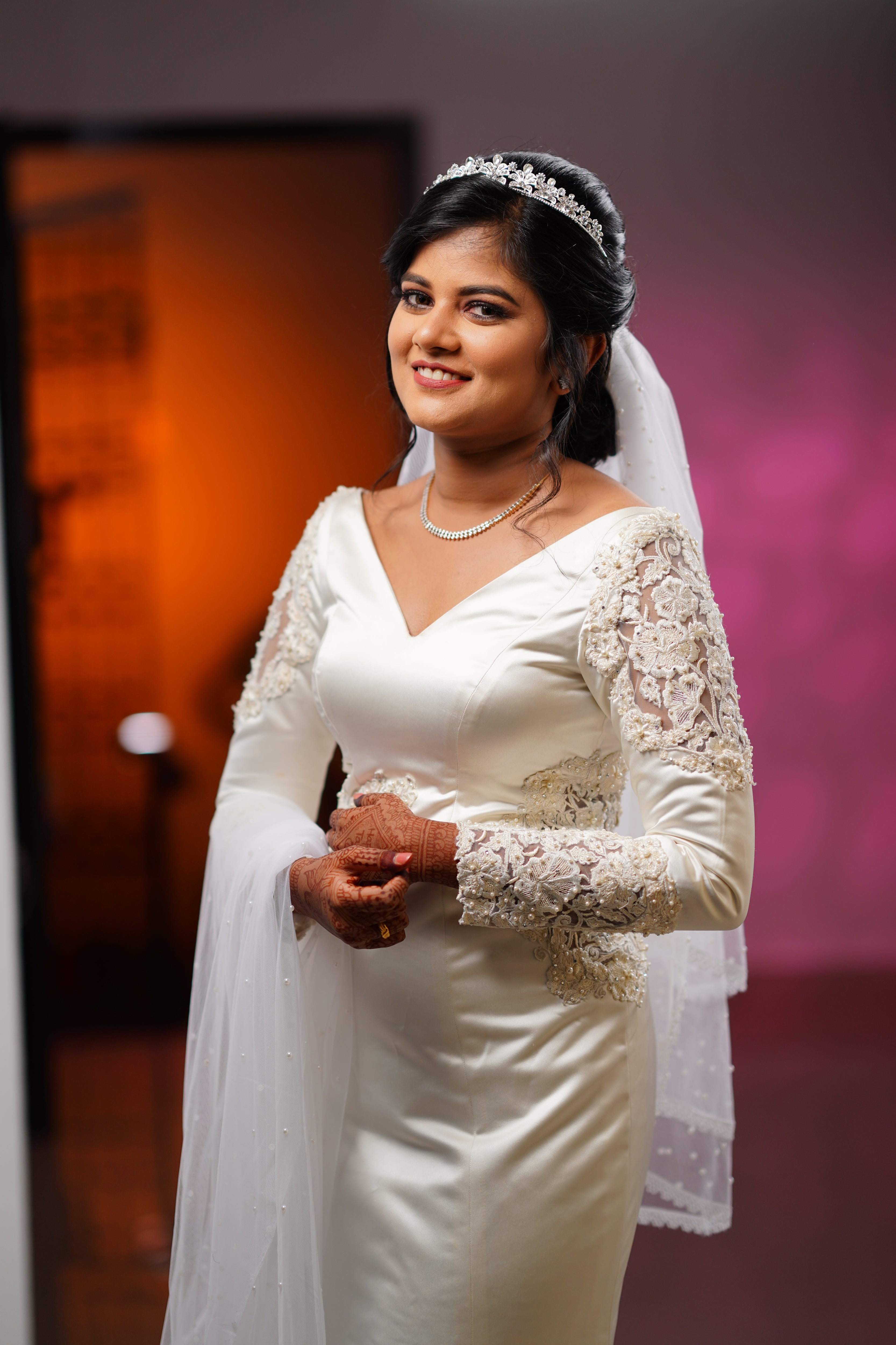 Adeal Josh smiling in a white gown for her church wedding, handcrafted by team Archana Karthick.