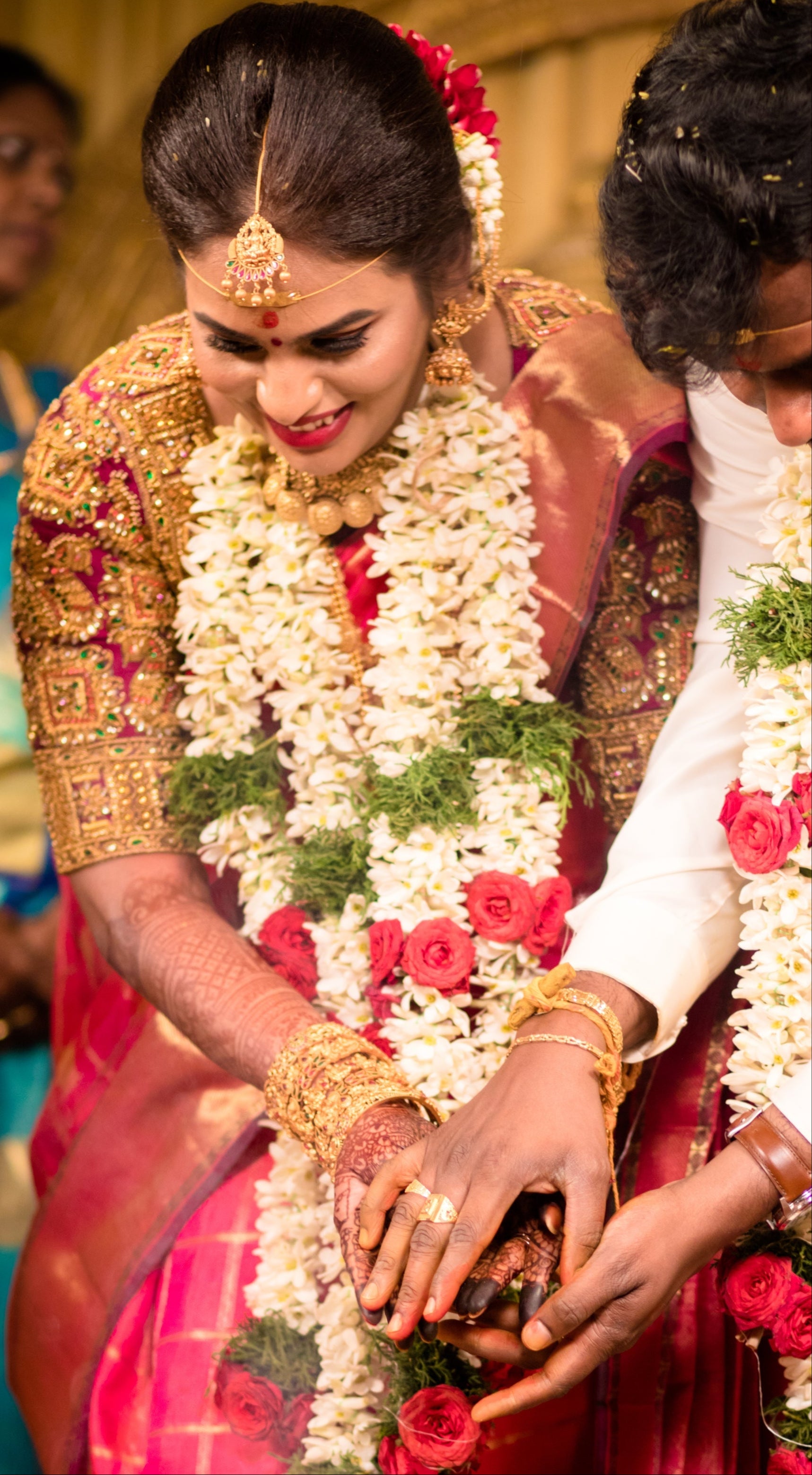Archana Karthick Bride Kowsalya in a concept bridal blouse in purple raw silk. The blouse is heavily embellished with zardozi, kemp stones, beads and is half or elbow sleeved. The bride is in the middle of her wedding ritual