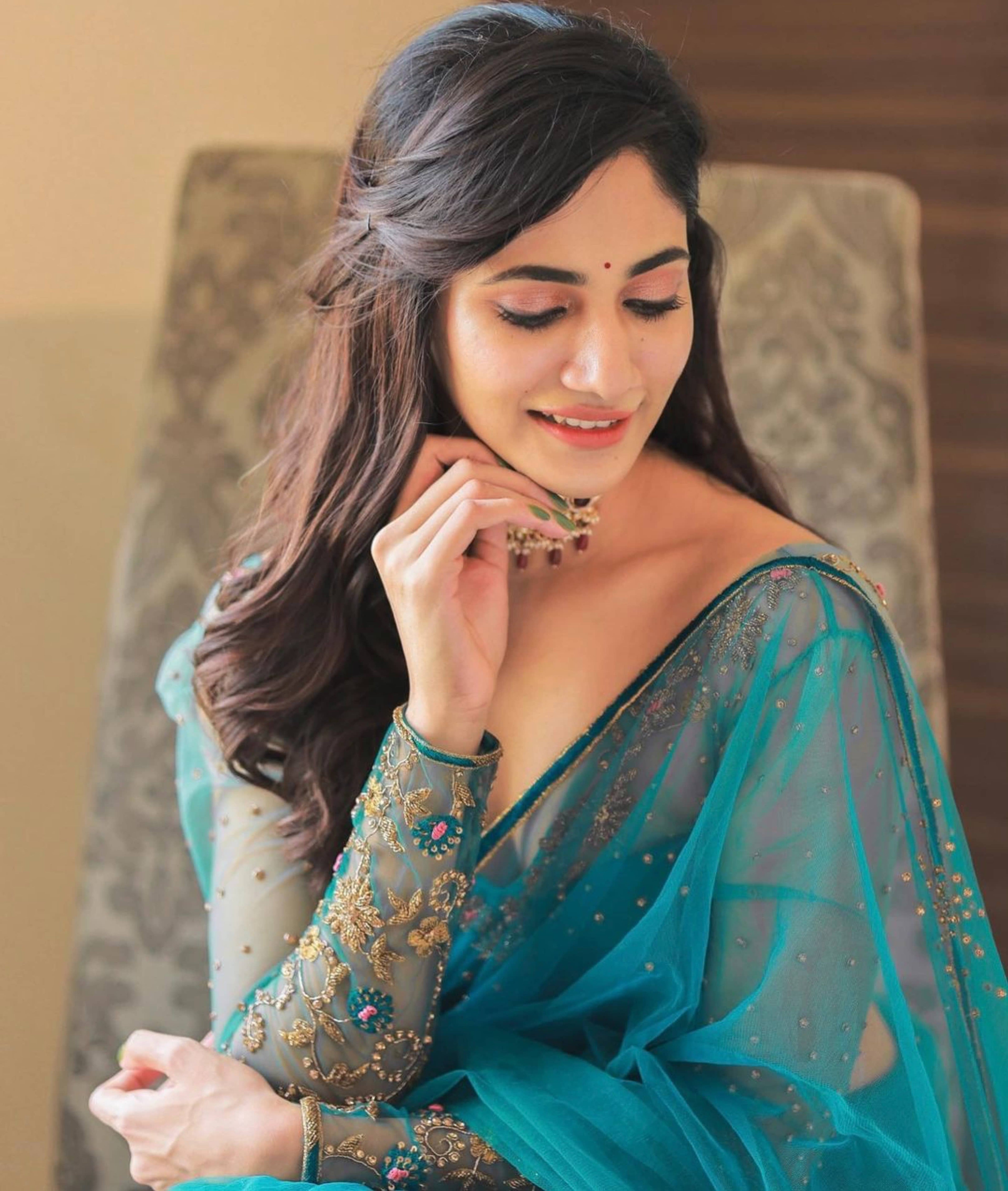 Bigg Boss fame and actress Losliya Mariyanesan in a teal blue handcrafted saree set designed by Archana Karthick.Looking down with a smile.