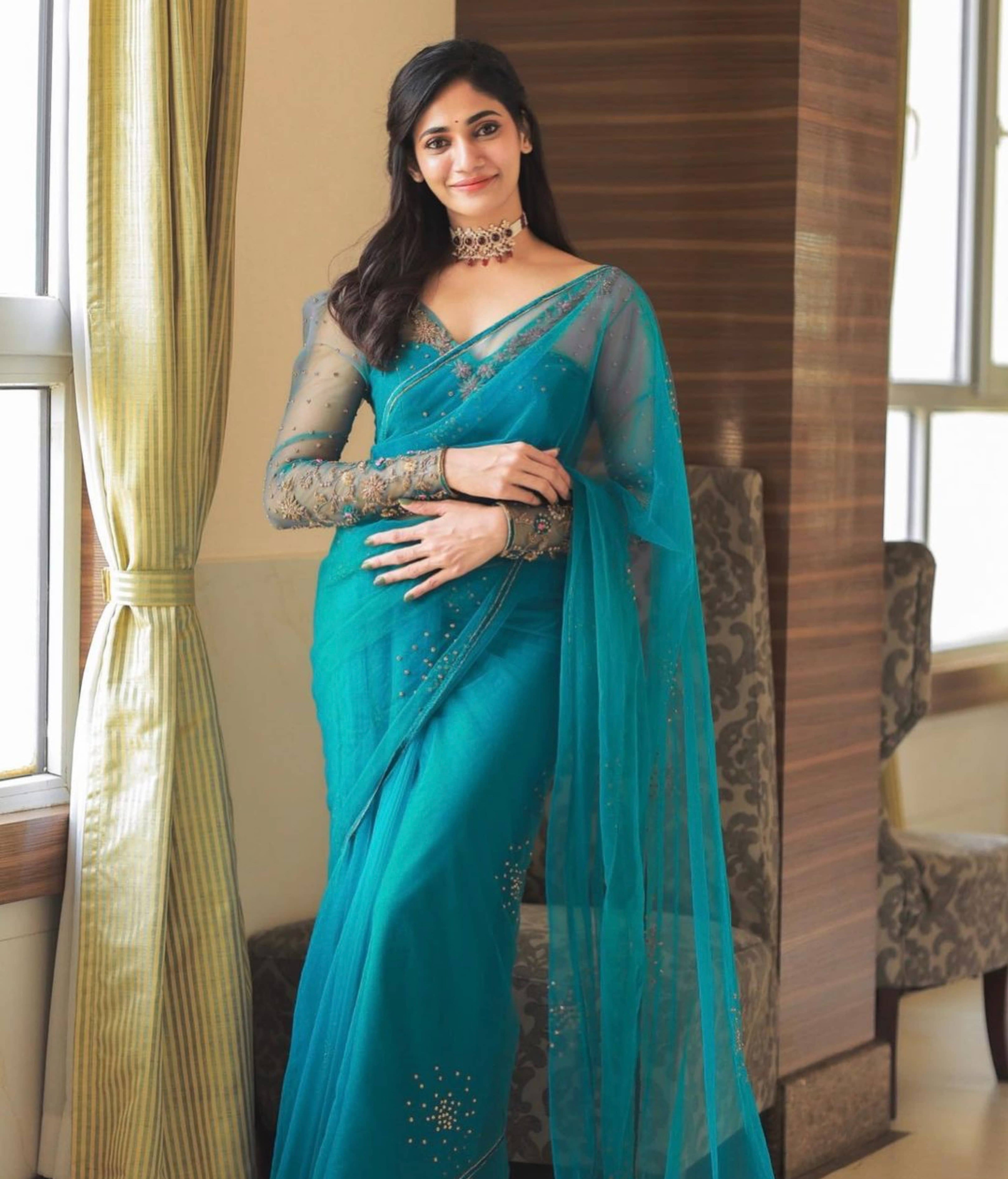 Bigg Boss fame and actress Losliya Mariyanesan in a teal blue handcrafted saree set designed by Archana Karthick. Looking straight ahead for a full profile picture.