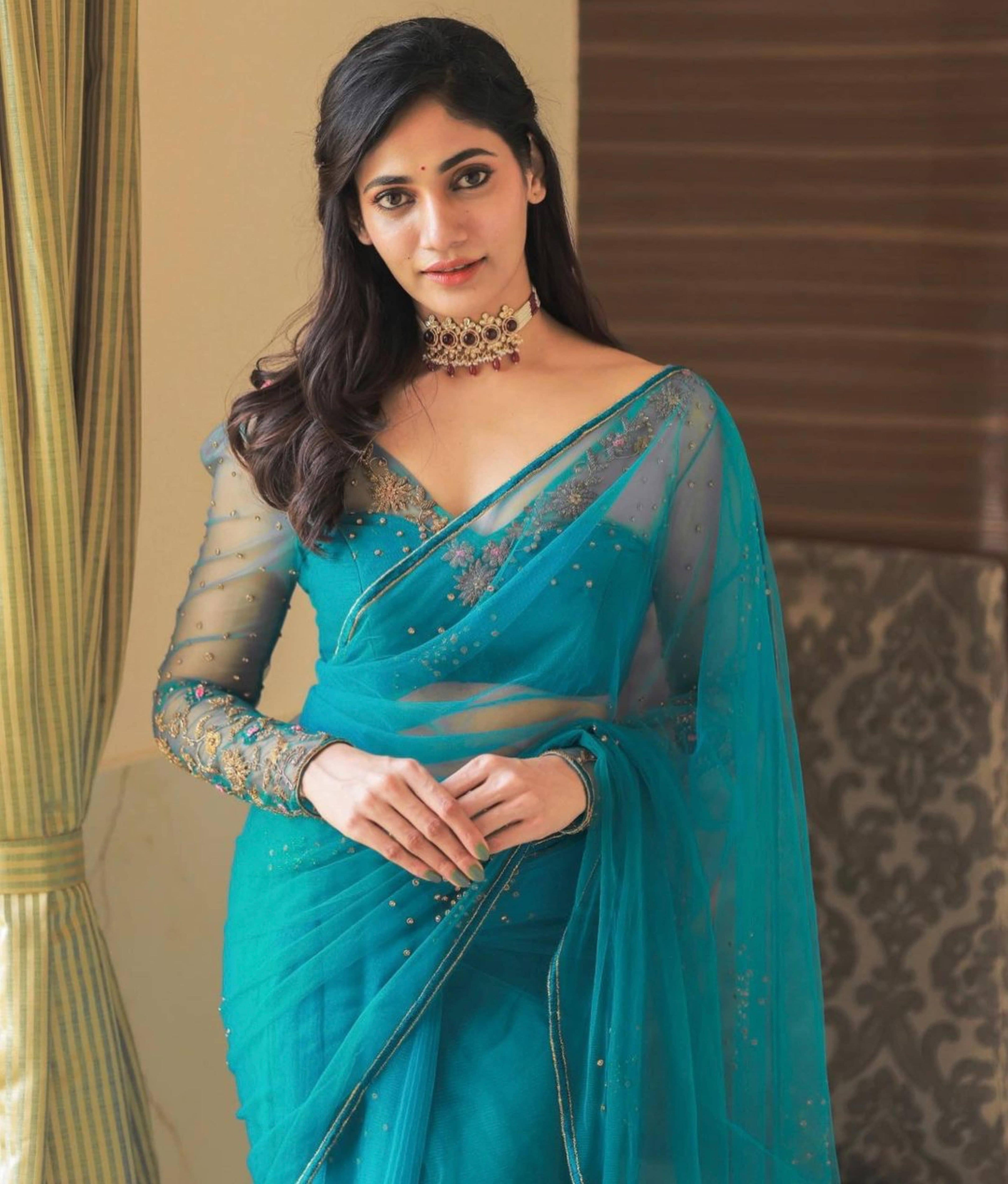 Bigg Boss fame and actress Losliya Mariyanesan in a teal blue handcrafted saree set designed by Archana Karthick. Looking straight at the camera.