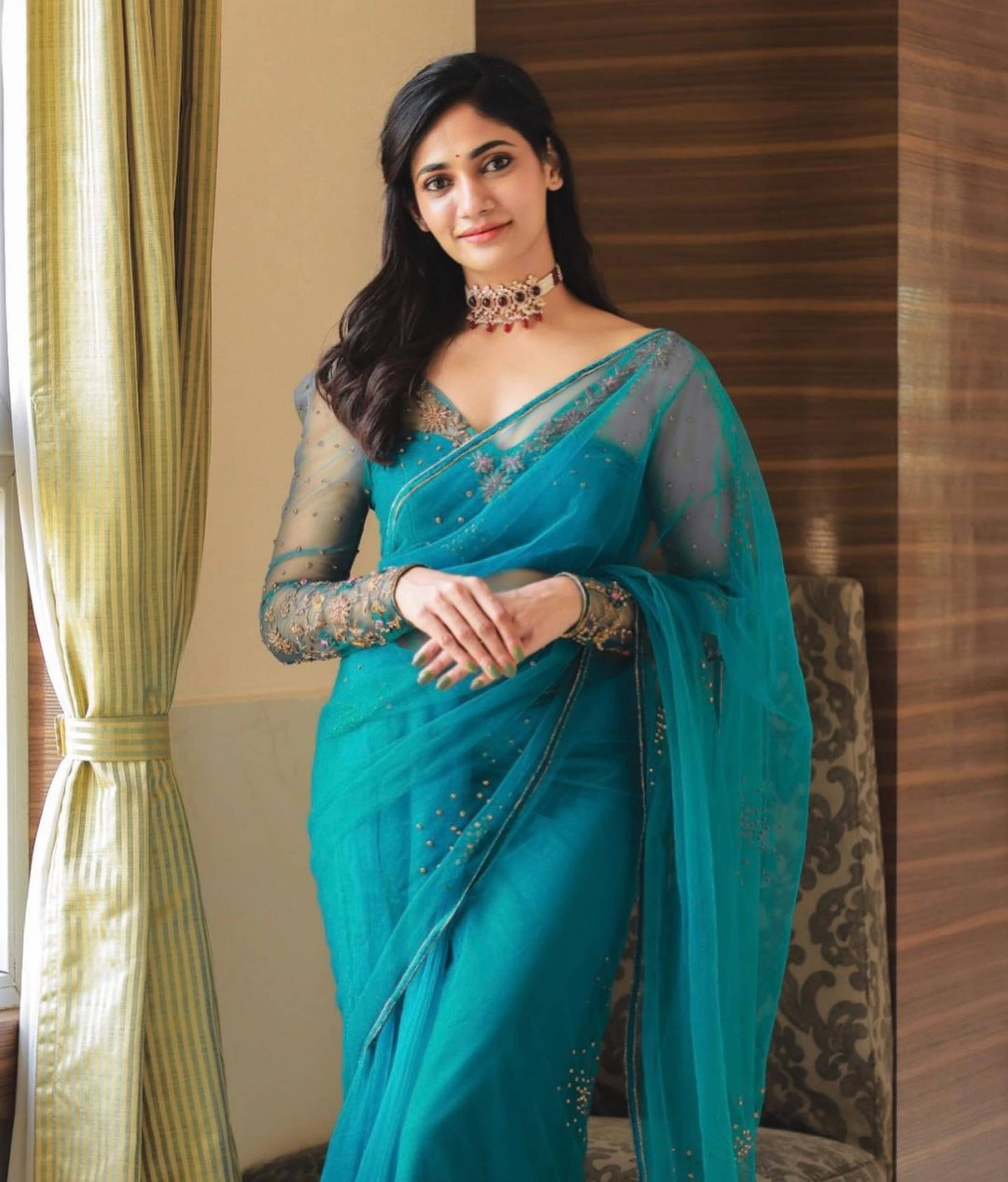 Bigg Boss fame and actress Losliya Mariyanesan in a teal blue handcrafted saree set designed by Archana Karthick. Looking straight at the camera and front fuill profile.