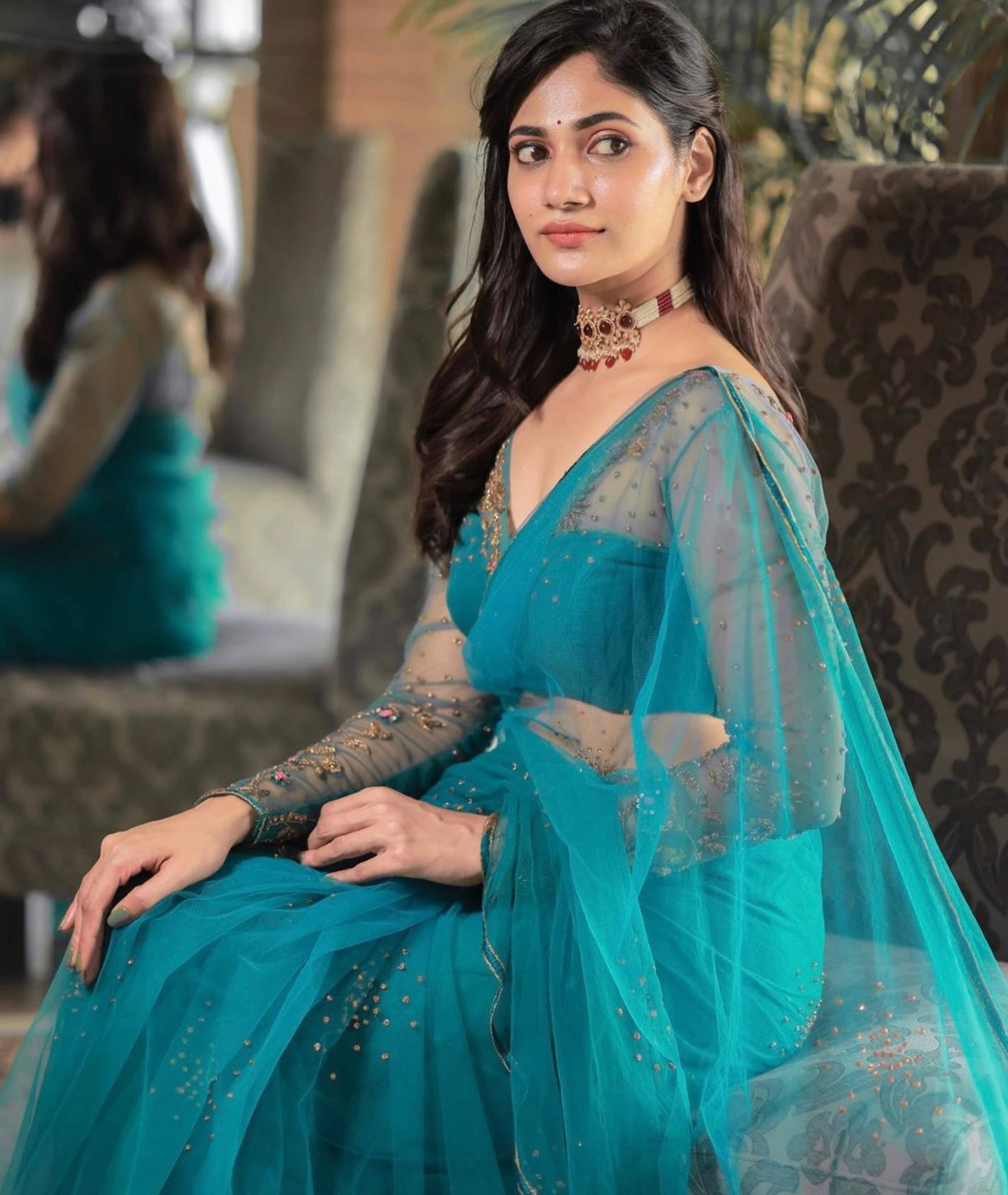 Bigg Boss fame and actress Losliya Mariyanesan in a teal blue handcrafted saree set designed by Archana Karthick. Looking to her right and blouse sleeeves and saree side profile.