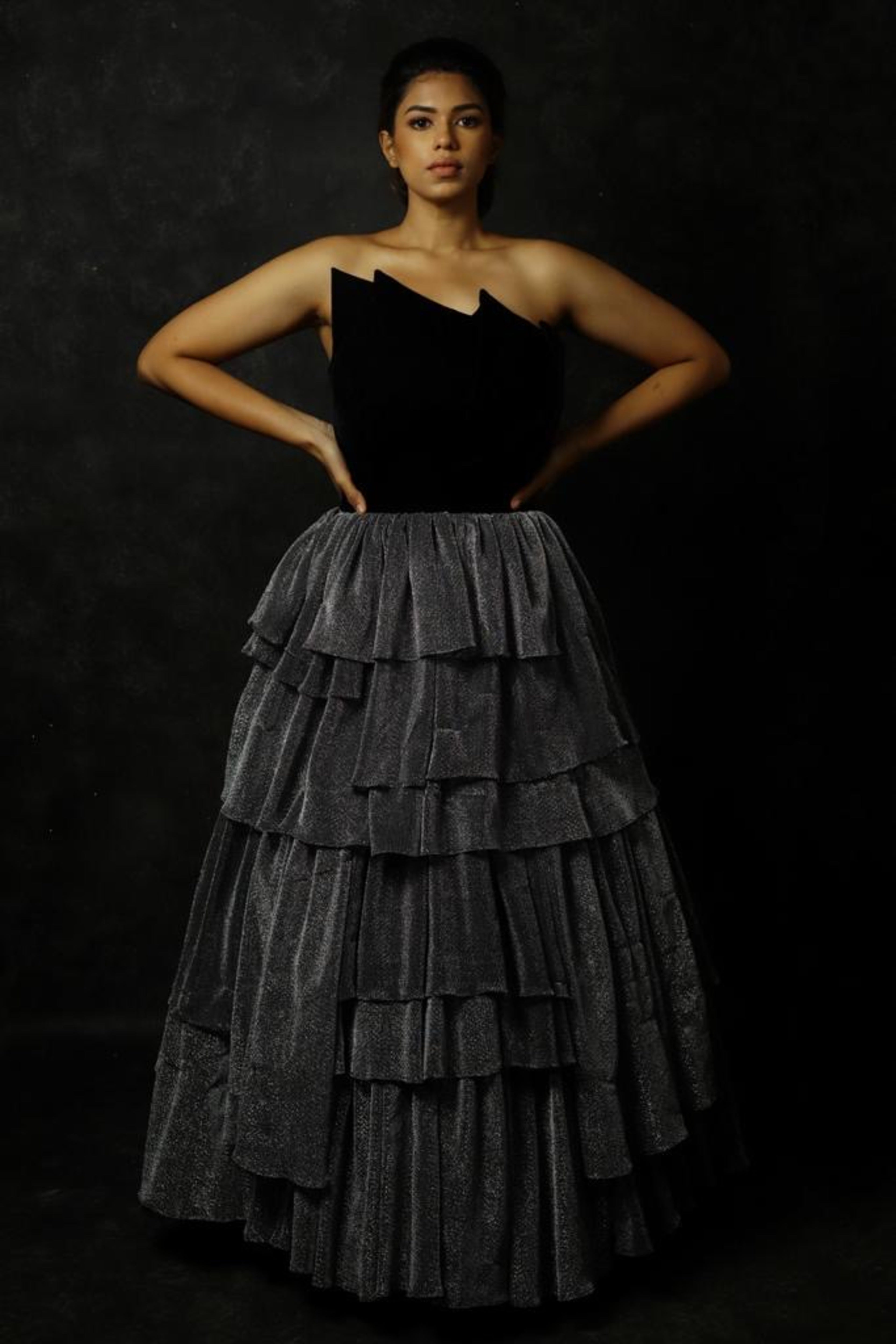 Black Velvet corset yoke with layered silver skirt gown designed by Archana Karthick. Actress Shrisha Full front profile.