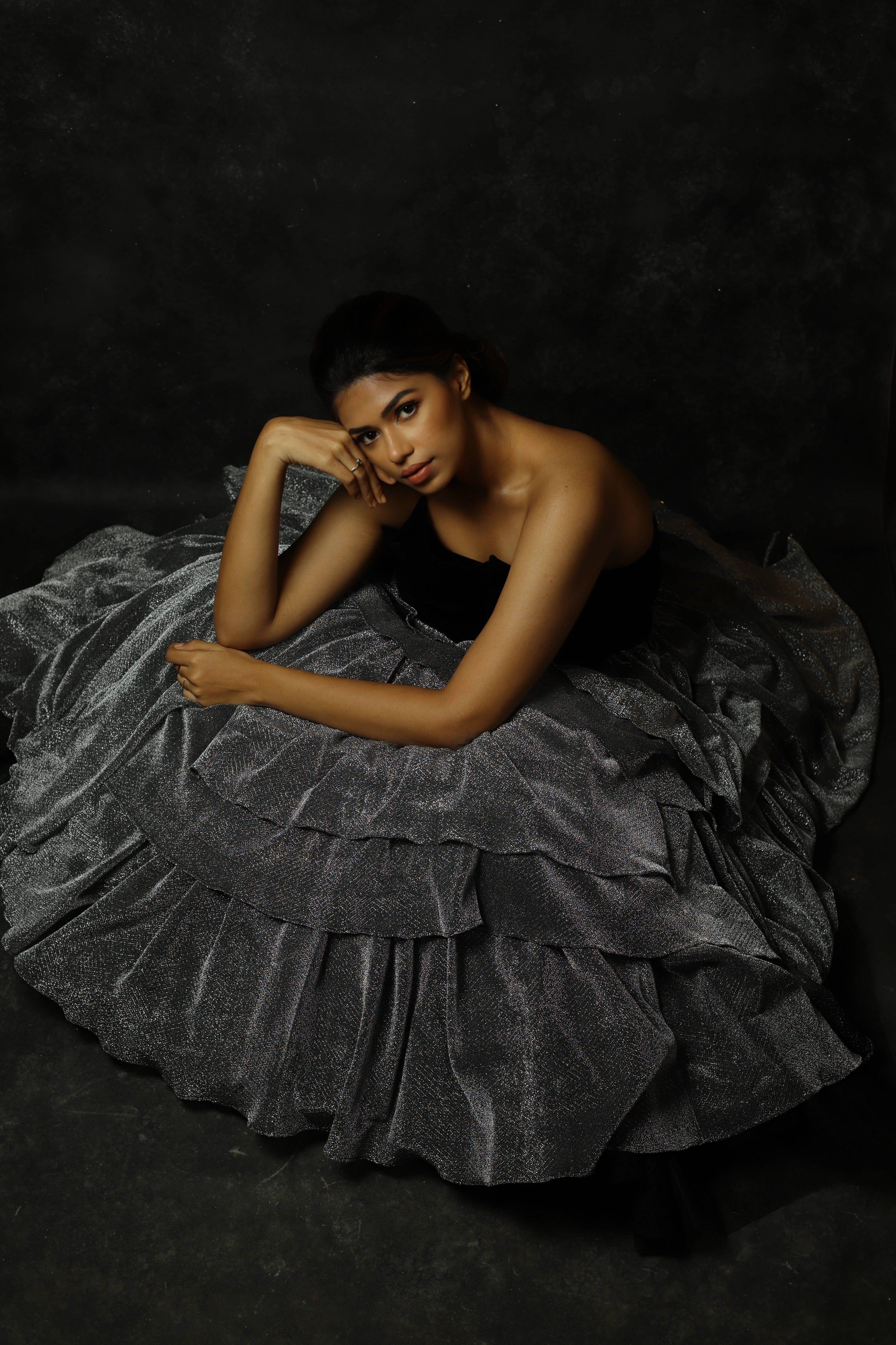 Black Velvet corset yoke with layered silver skirt gown designed by Archana Karthick. Actress Shrisha Seated picture.
