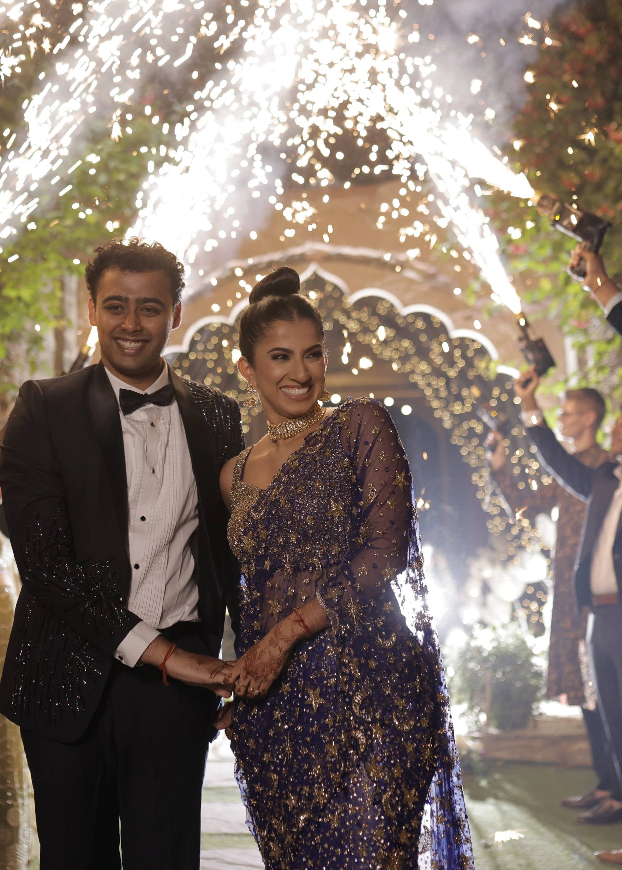 Bride Aashi Pal smiling for photo in a midnight blue tulle draped lehenga, handcrafted by team Archana Karthick.