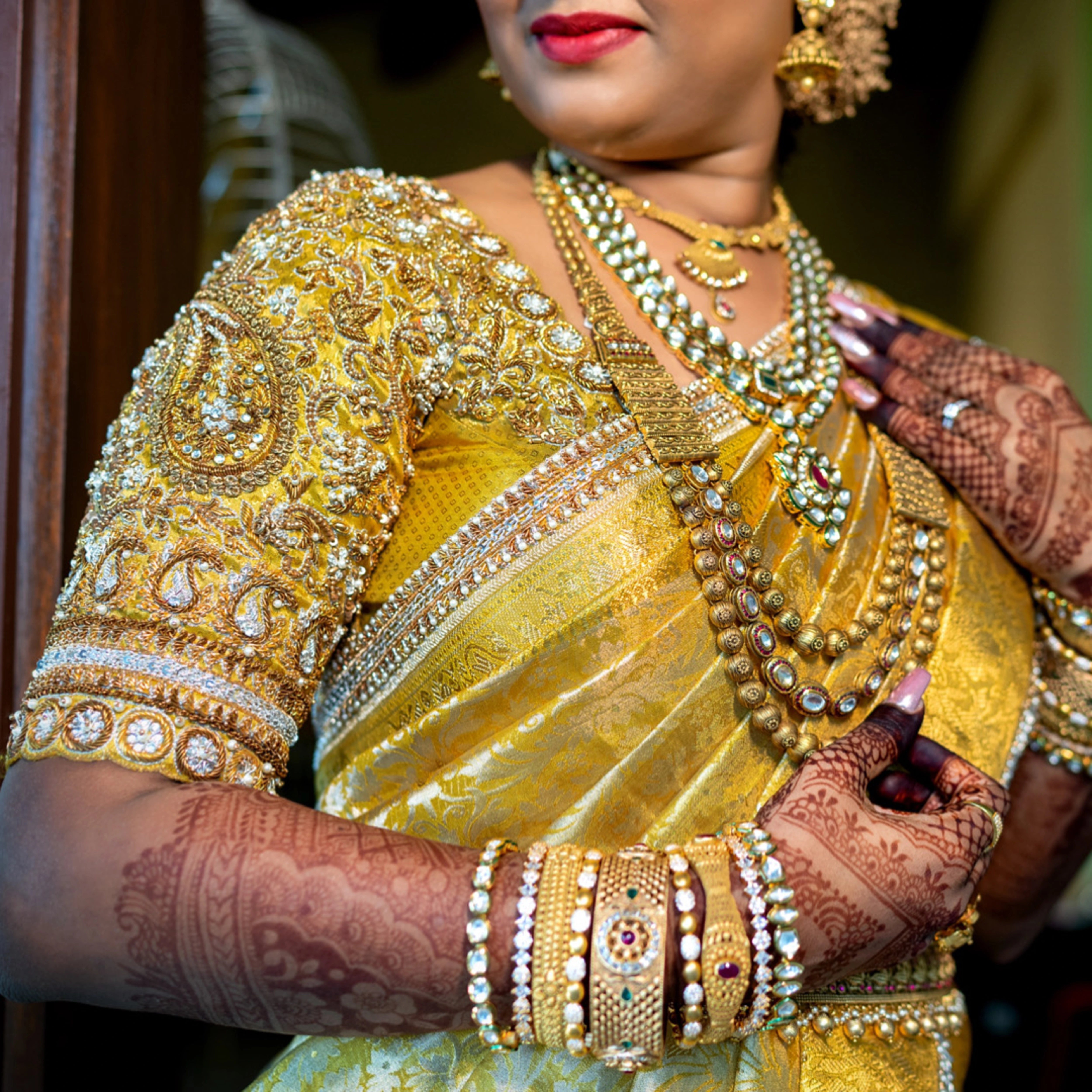 Bride Abinaya V showcasing blouse sleeve in a gold concept silk blouse and saree border, intricately handcrafted with zardosi, beads, stone, zari and pearls by team Archana Karthick.