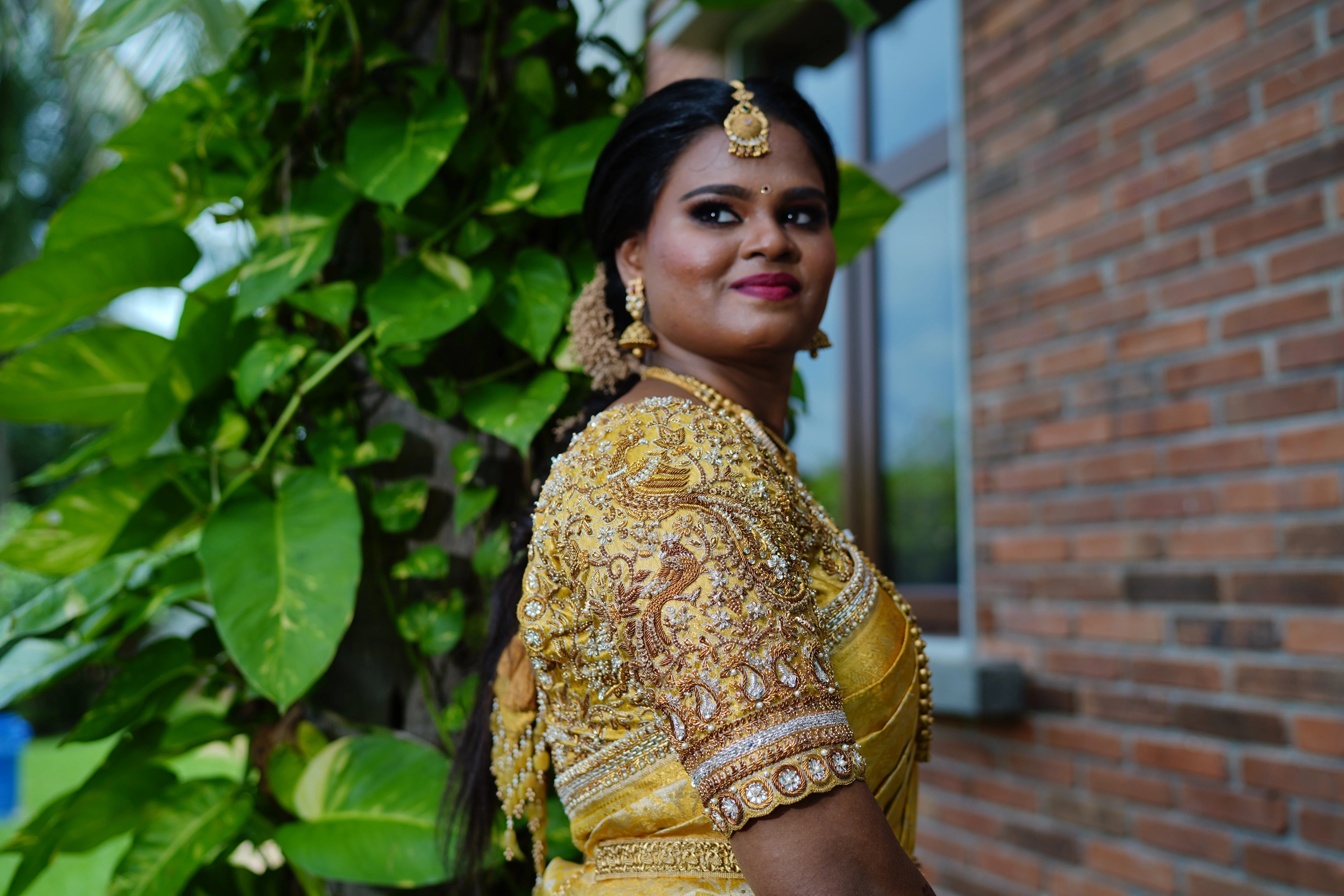Bride Abinaya smiling in a gold concept silk blouse and saree border, intricately handcrafted by team Archana Karthick.