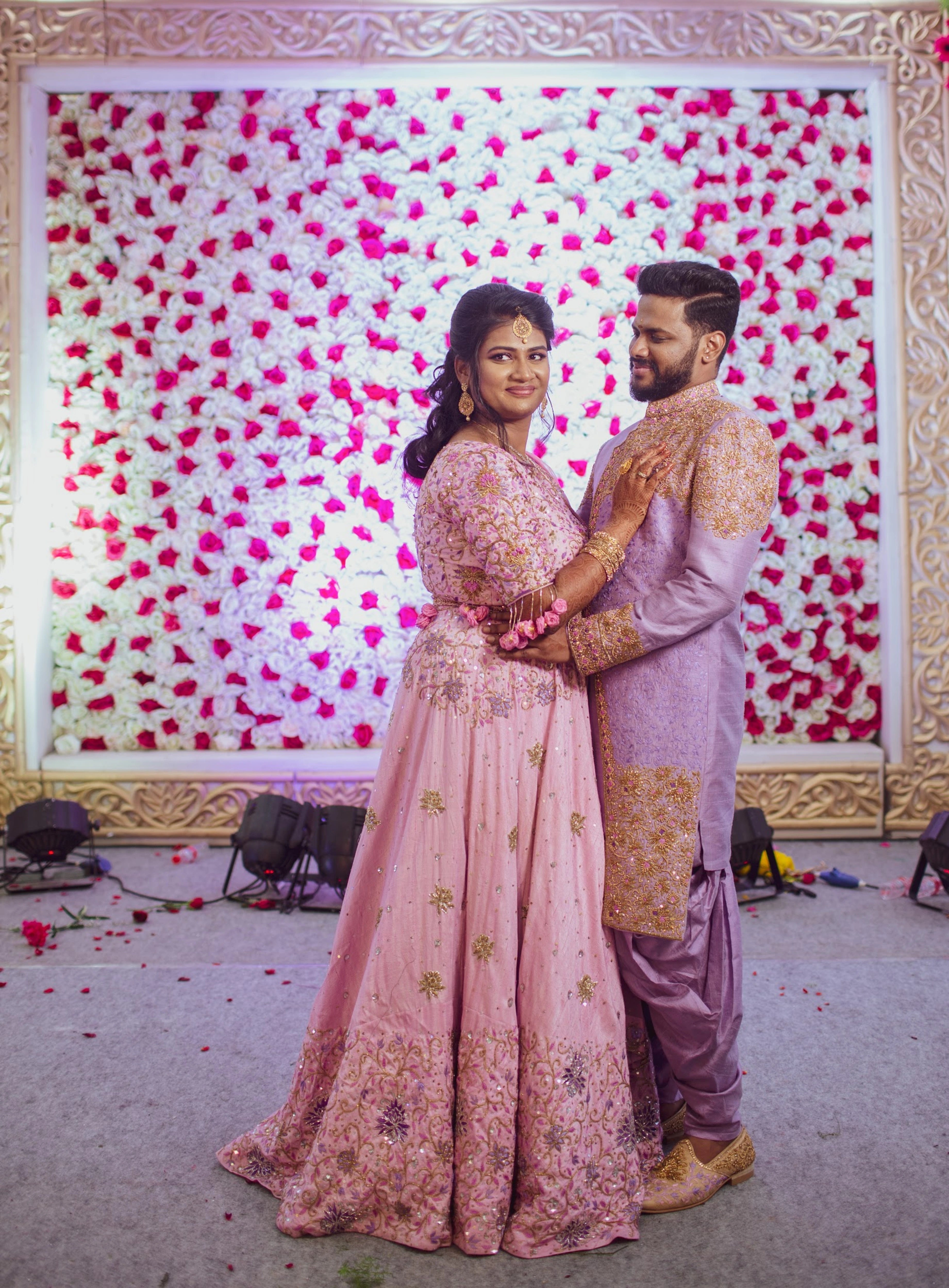 Bride Aishwarya & Groom Nirmal in shades of pink and lavender raw silk lehenga and indowestern sherwani, intricately handcrafted by team Archana Karthick.