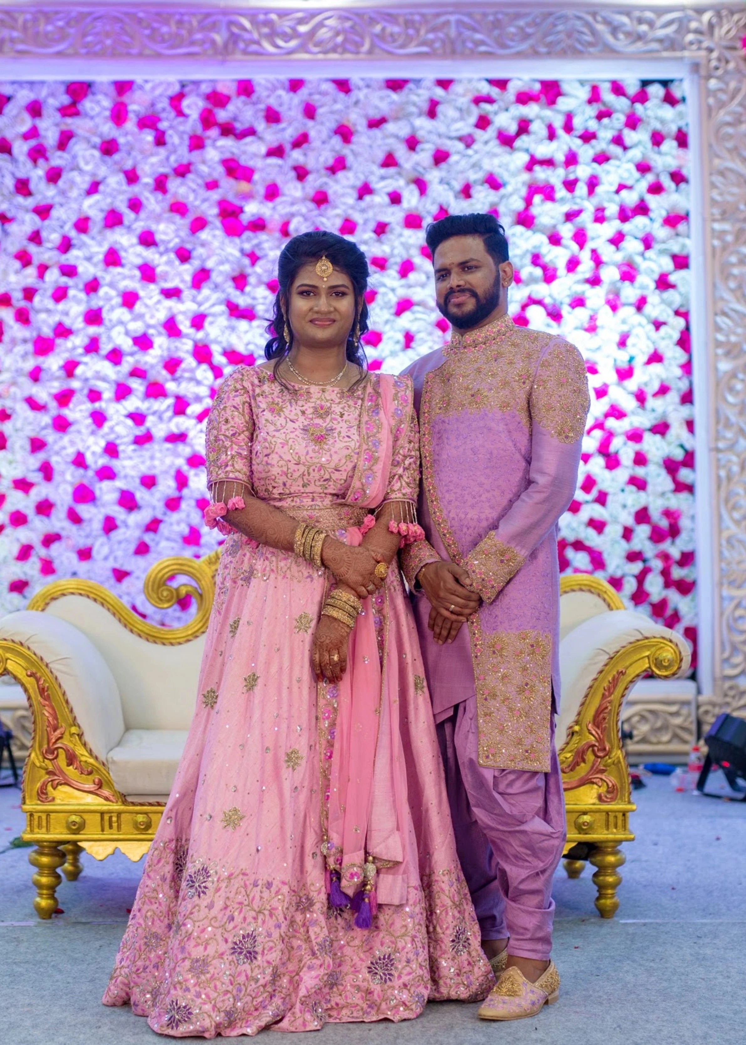 Bride Aishwarya & Groom Nirmal on stage in shades of pink and lavender raw silk lehenga and indowestern sherwani, intricately handcrafted by team Archana Karthick.