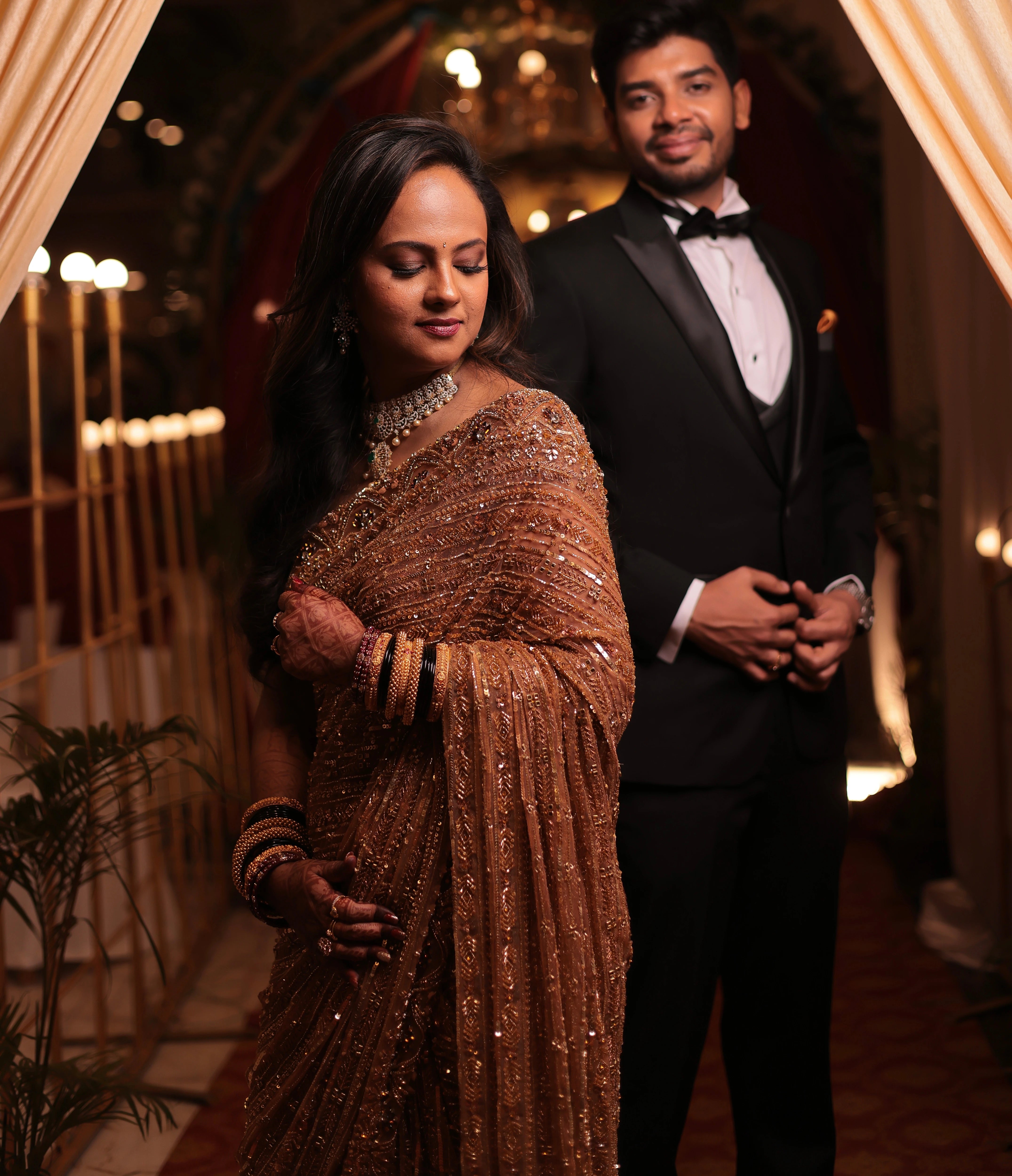 Bride Aishwarya from USA, posing with groom in a golden tulle saree handcrafted by team Archana Karthick.