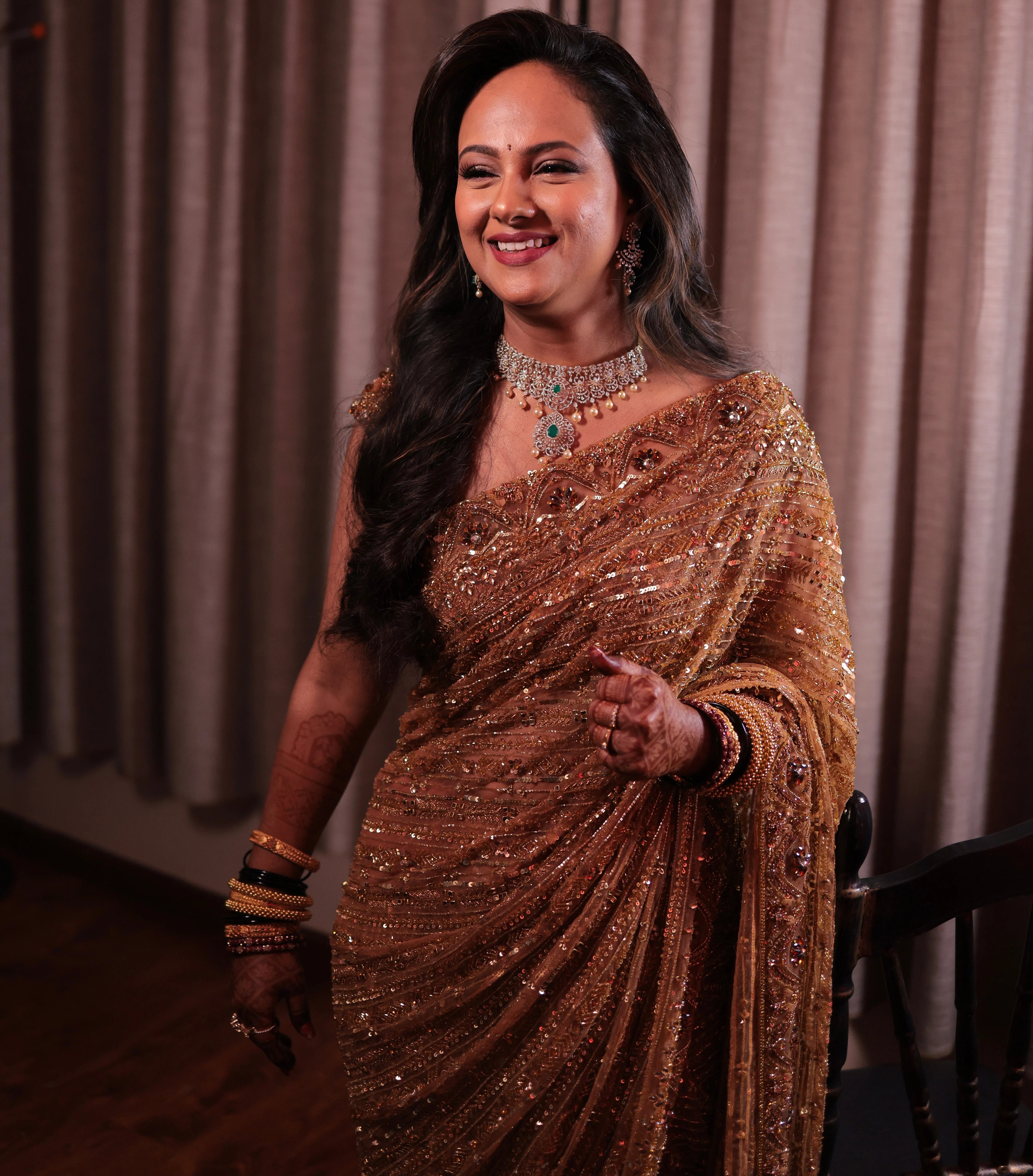 Bride Aishwarya from USA, smiling in a golden tulle saree handcrafted by team Archana Karthick.