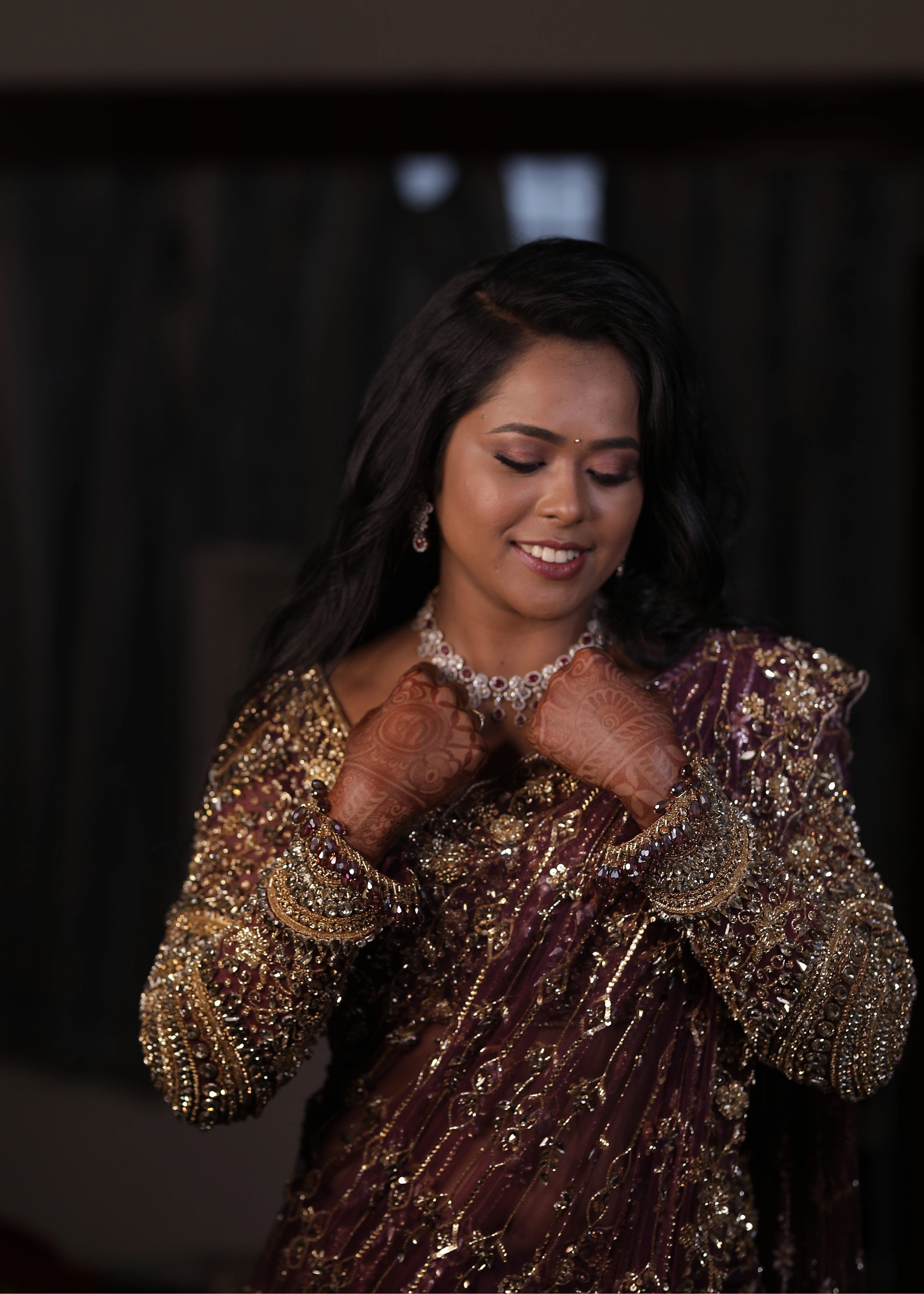 Bride Akalya smiling for photo in a wine red tulle saree handcrafted by team Archana Karthick.