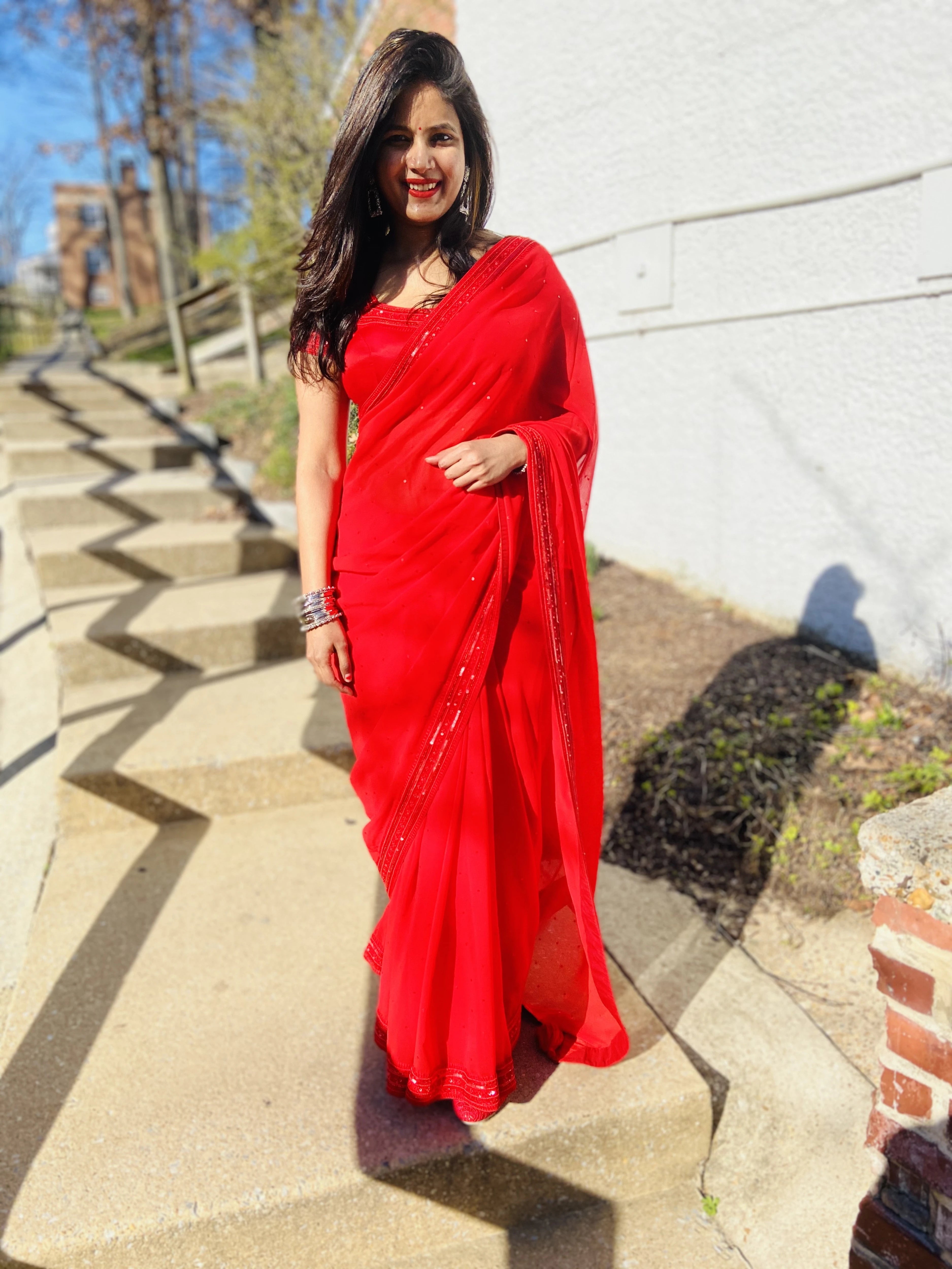 Bride Ankita laughing in a red georgette saree and blouse handcrafted by team Archana Karthick.