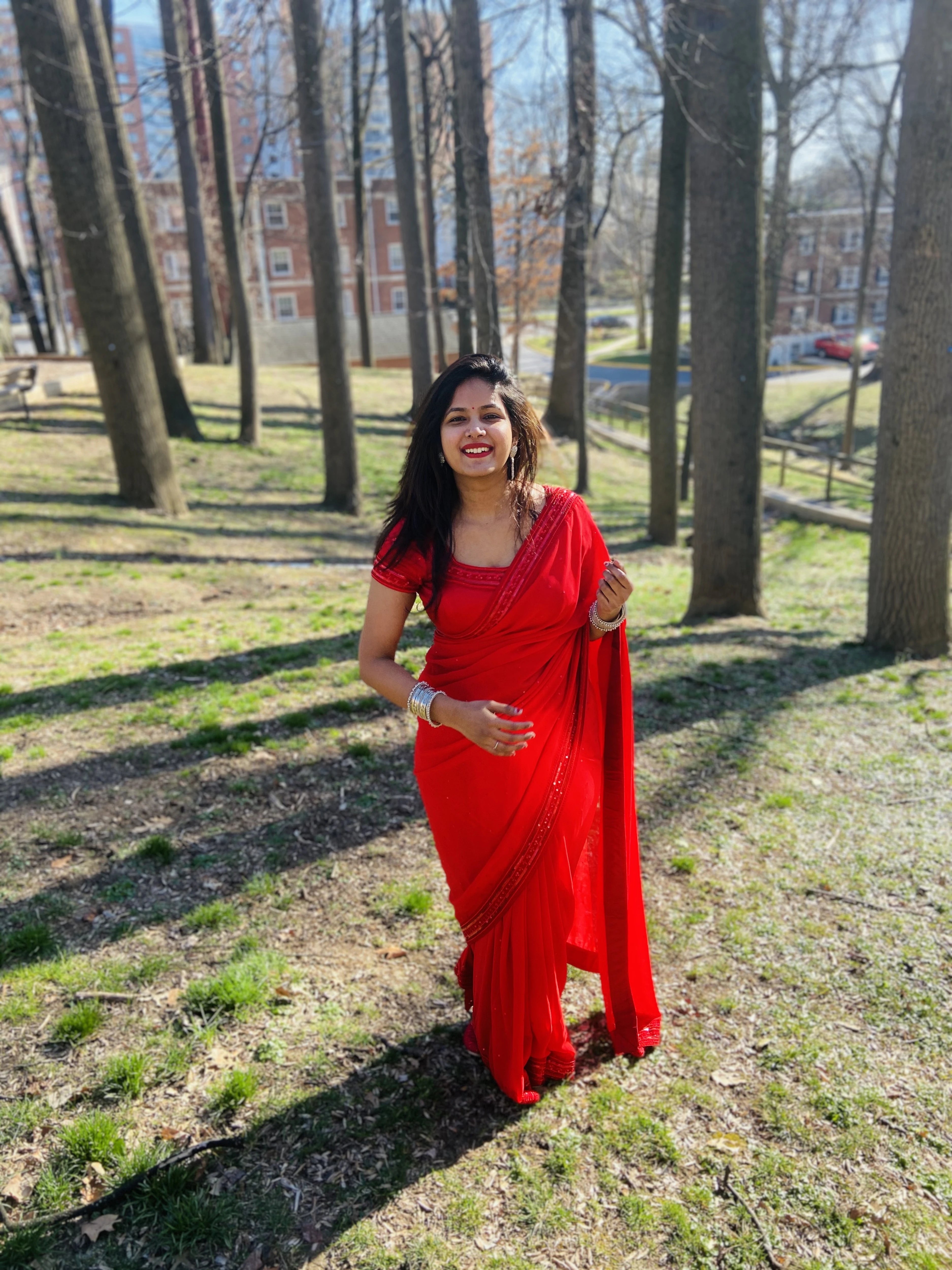 Bride Ankita smiling and posing in a red georgette saree and blouse handcrafted by team Archana Karthick.