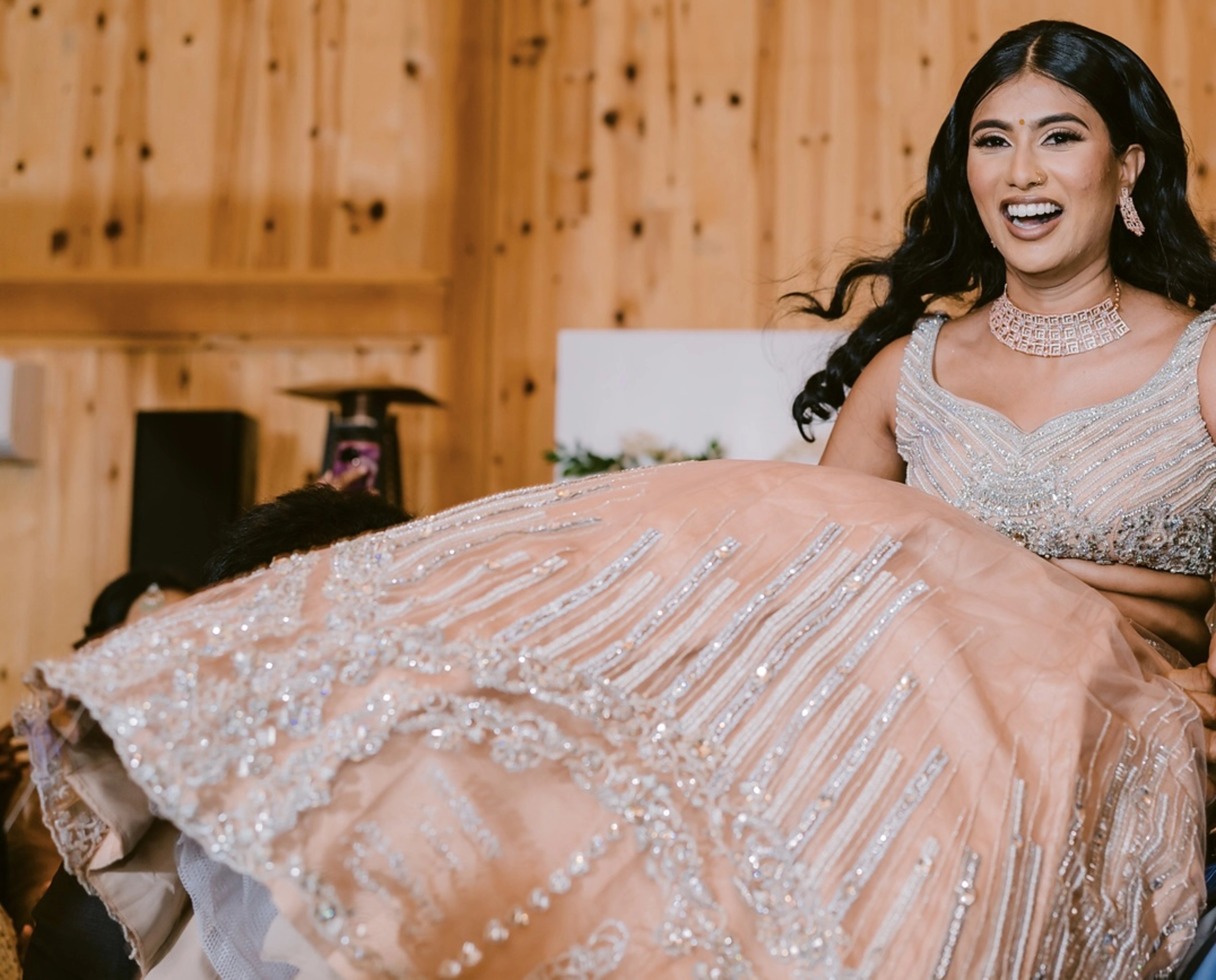 Bride Apy from Canada being carried in a blush (shades of peach cream) lehenga, handcrafted by team Archana Karthick.