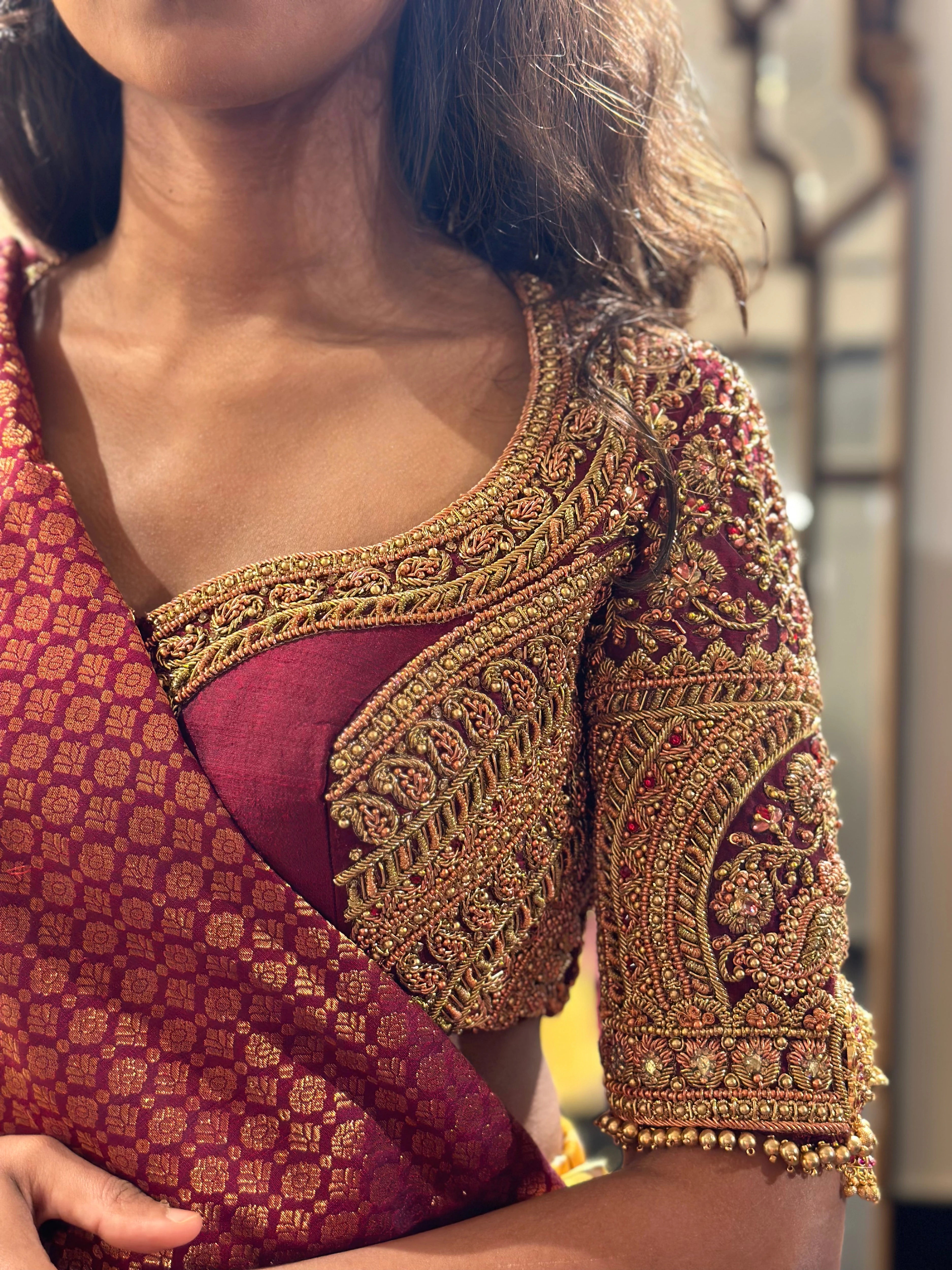Bride Ashwathi during fittings for her wedding in a maroon silk blouse, handcrafted by team Archana Karthick.