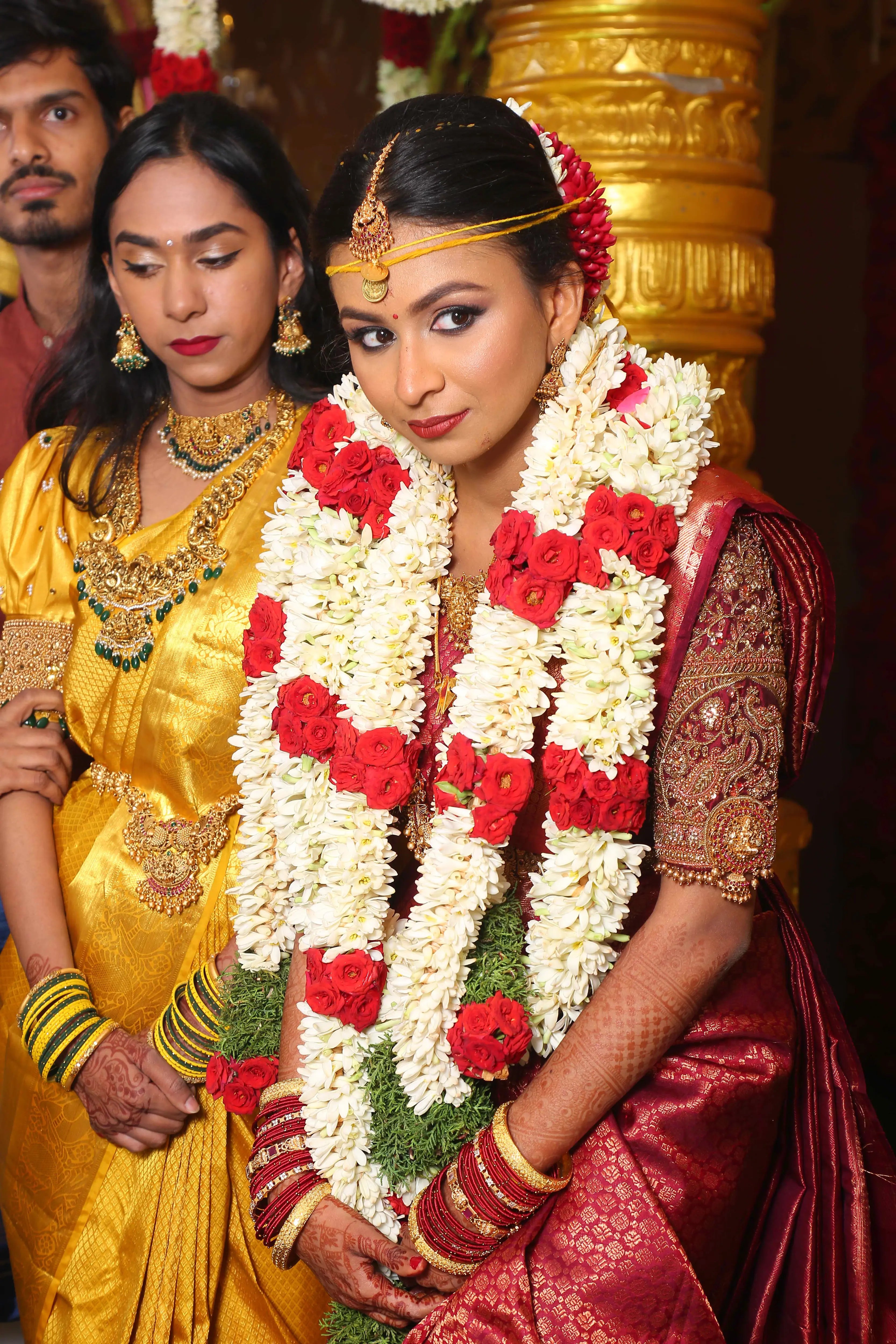 Bride Ashwathi during her wedding in a maroon silk blouse, handcrafted by team Archana Karthick.