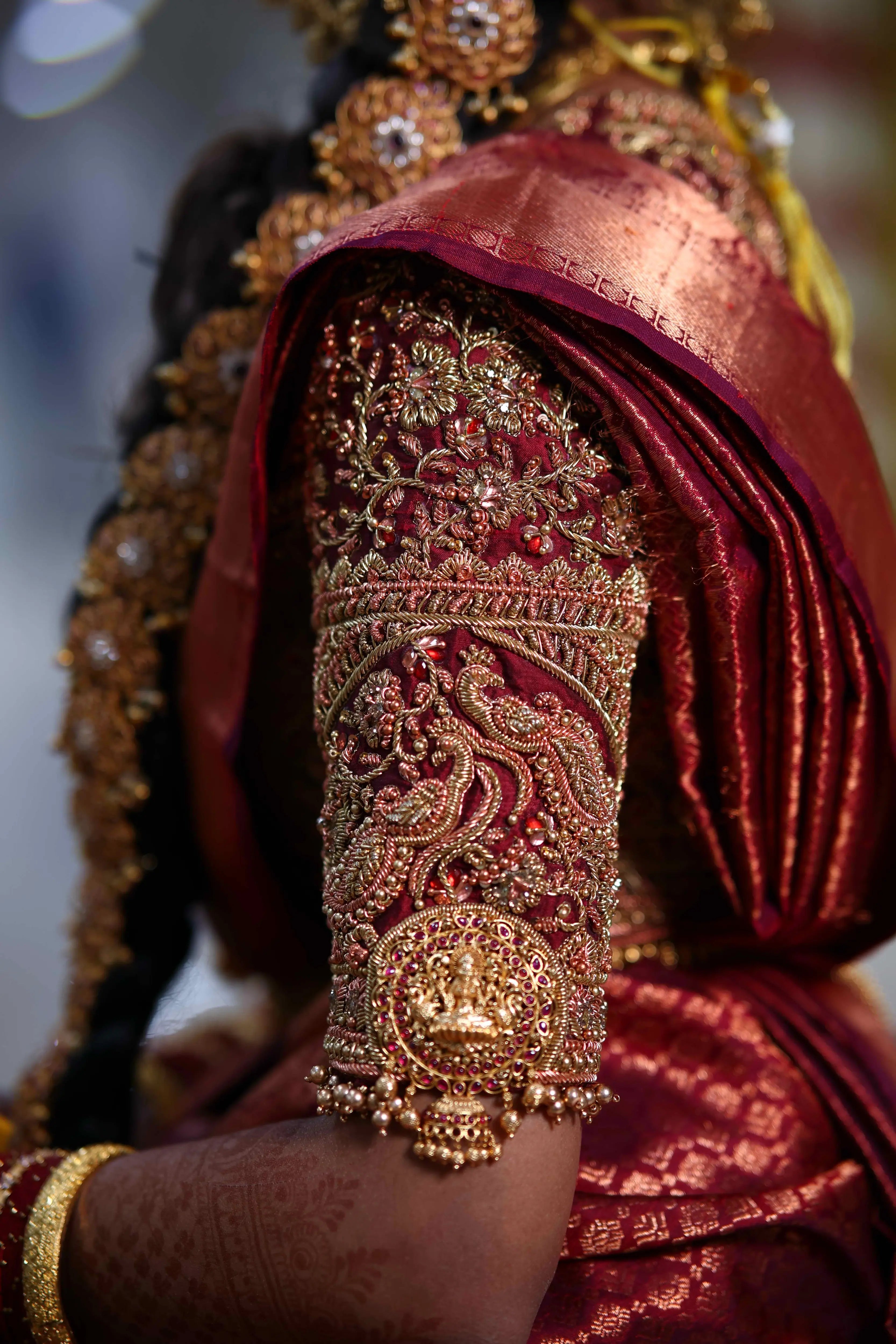 Bride Ashwathi from Dindigul posing in a maroon concept silk blouse, intricately handcrafted with zardosi, beads, kundan, sequins and kemp stones by team Archana Karthick.