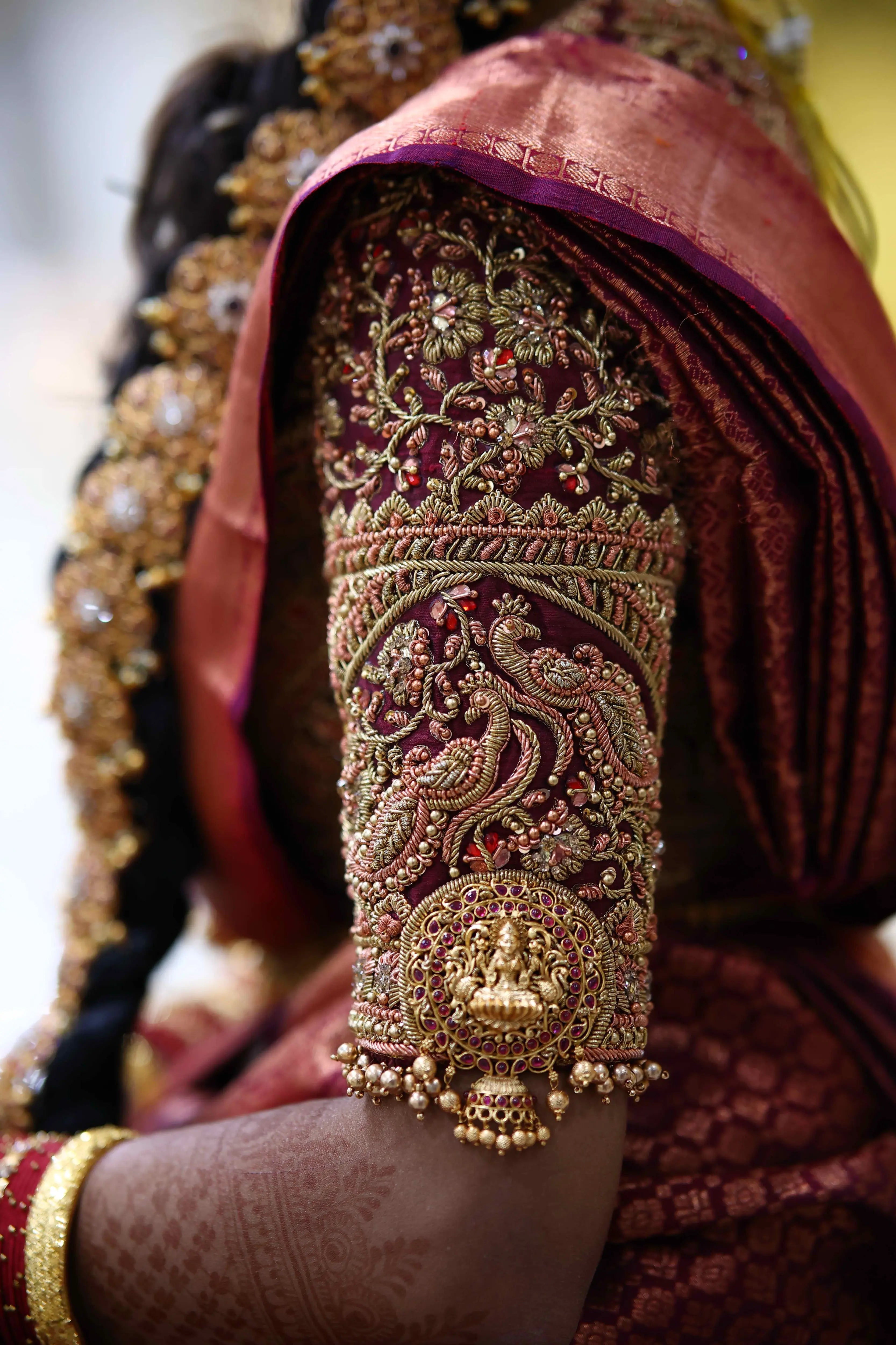 Bride Ashwathi from Dindigul showcasing blouse sleeve design in a maroon concept silk blouse, intricately handcrafted with zardosi, beads, kundan, sequins and kemp stones by team Archana Karthick.